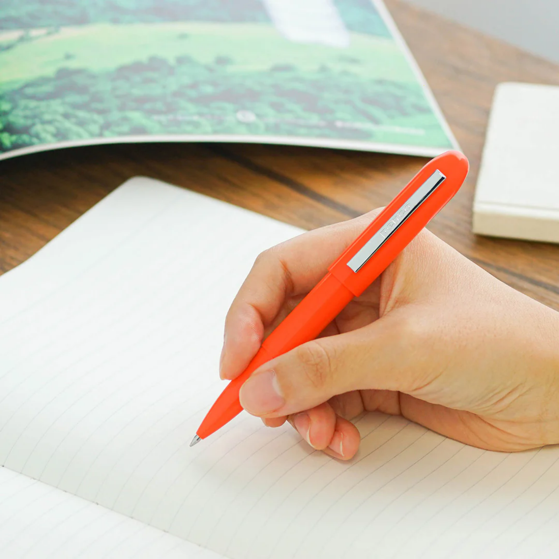 Woman holding Penco small ballpoint pen orange writing on paper