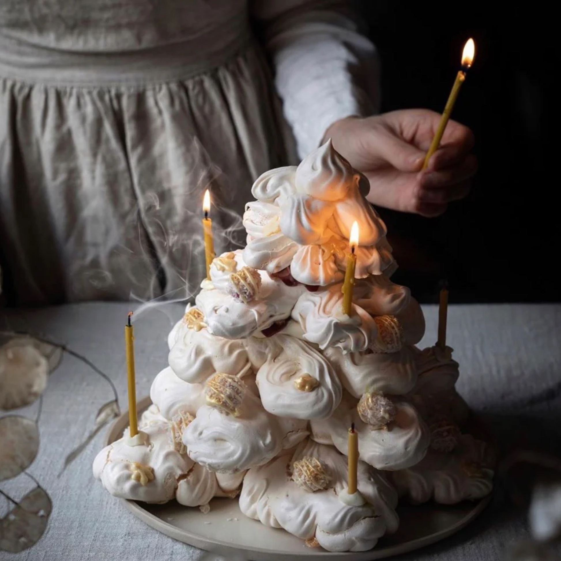 Woman placing Queen Bee candles in cake on linen table cloth