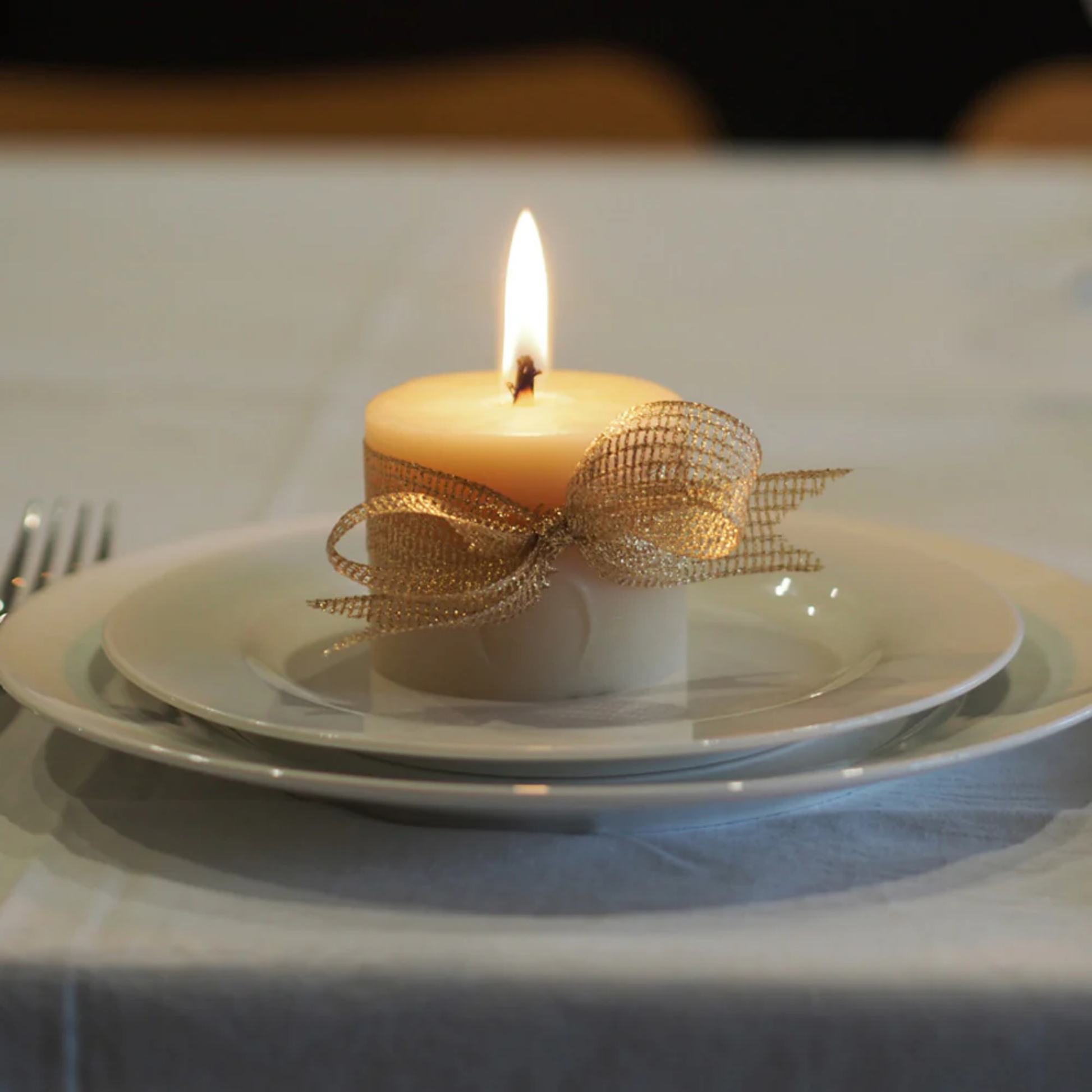 Queen Bee beeswax pillar squat candle with ribbon on plates at table
