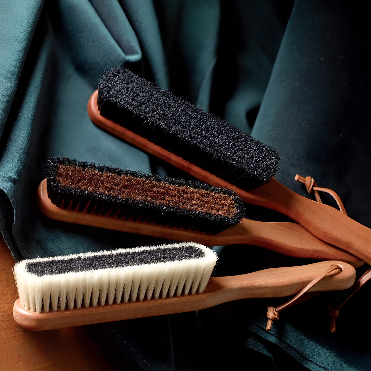 Three variants of clothes brush including the Redecker Cashmere Clothes Brush made from oiled pearwood handle and black plus soft light bristles in the outer for removal of lint, fuzz, hair or dust on all clothing.