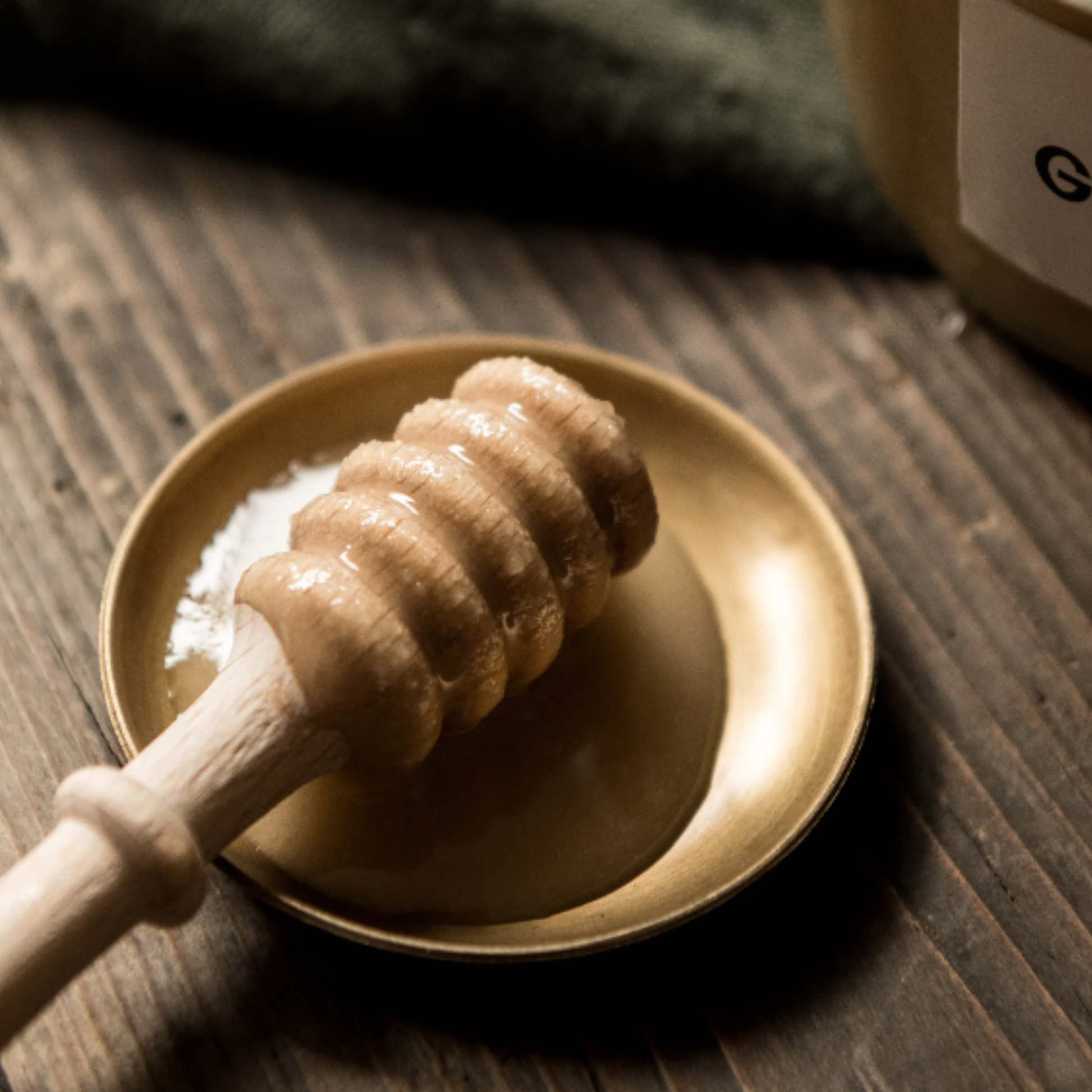 Redecker honey spoon on display with honey on spoon resting on small brass dish on wooden table