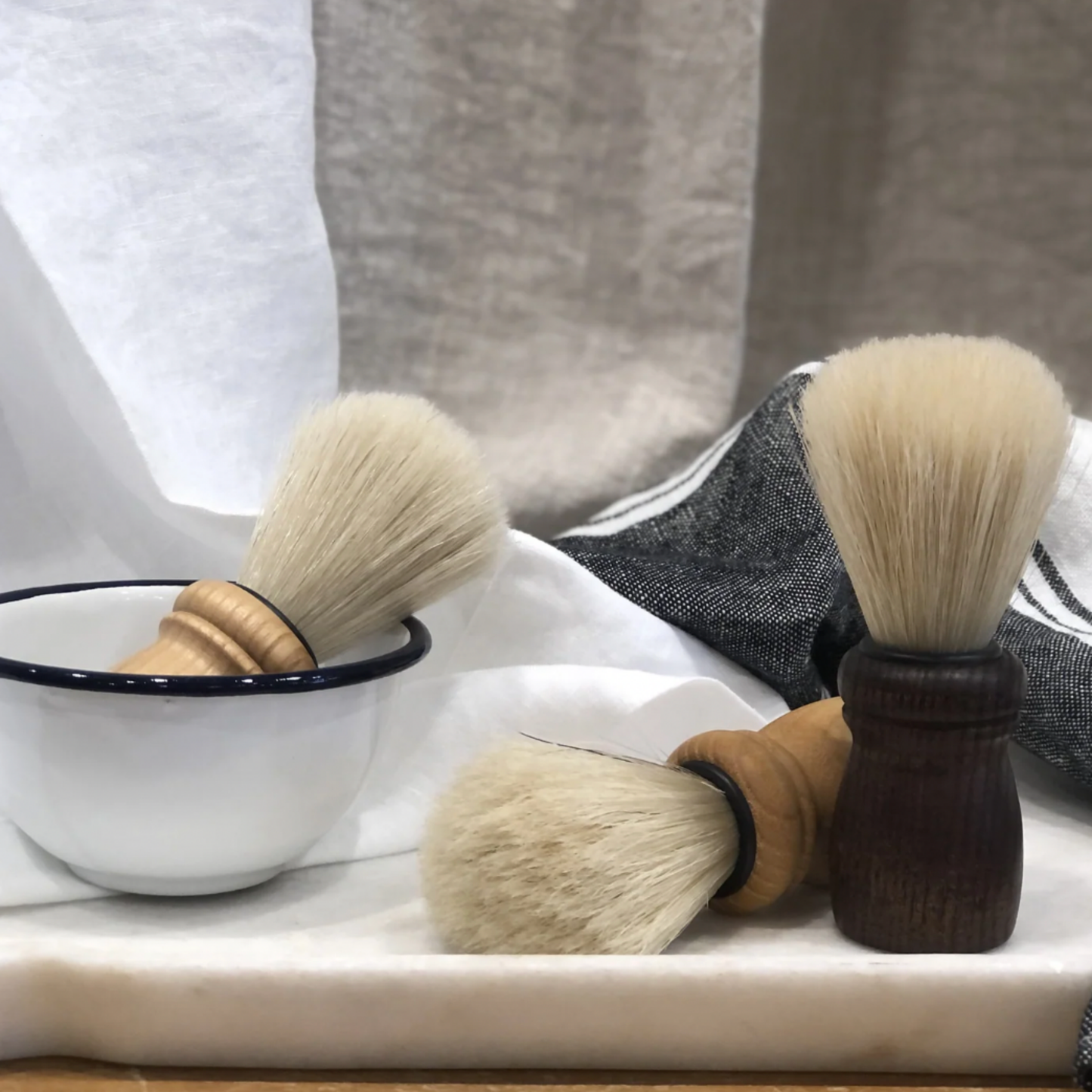 Assorted Redecker shaving brushed on display infront of linen in a bowl 