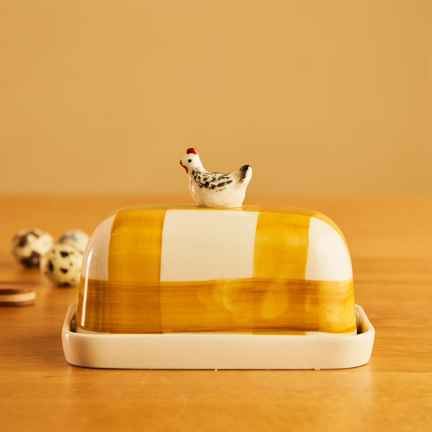 Side view of the Robert Gordon Butter Dish Chook made from high fired porcelain with orange brushwork lines and a hand-painted chicken perched on top.