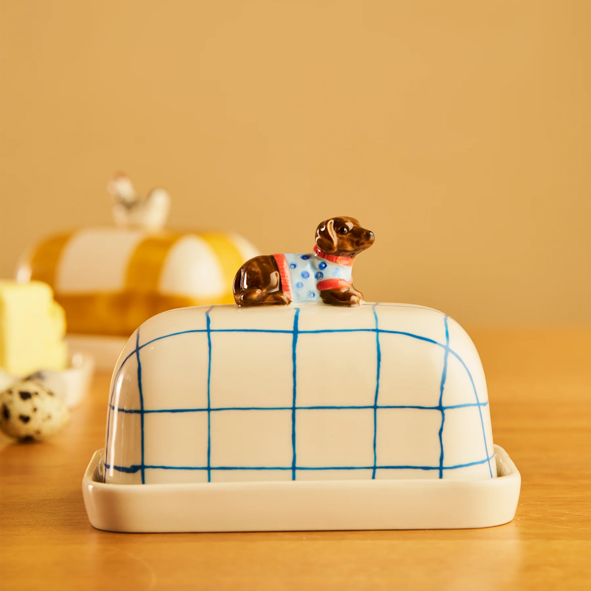 Side view of the Robert Gordon Butter Dish Dachshund made from high fired porcelain with blue brushwork lines and a hand-painted dog perched on top.