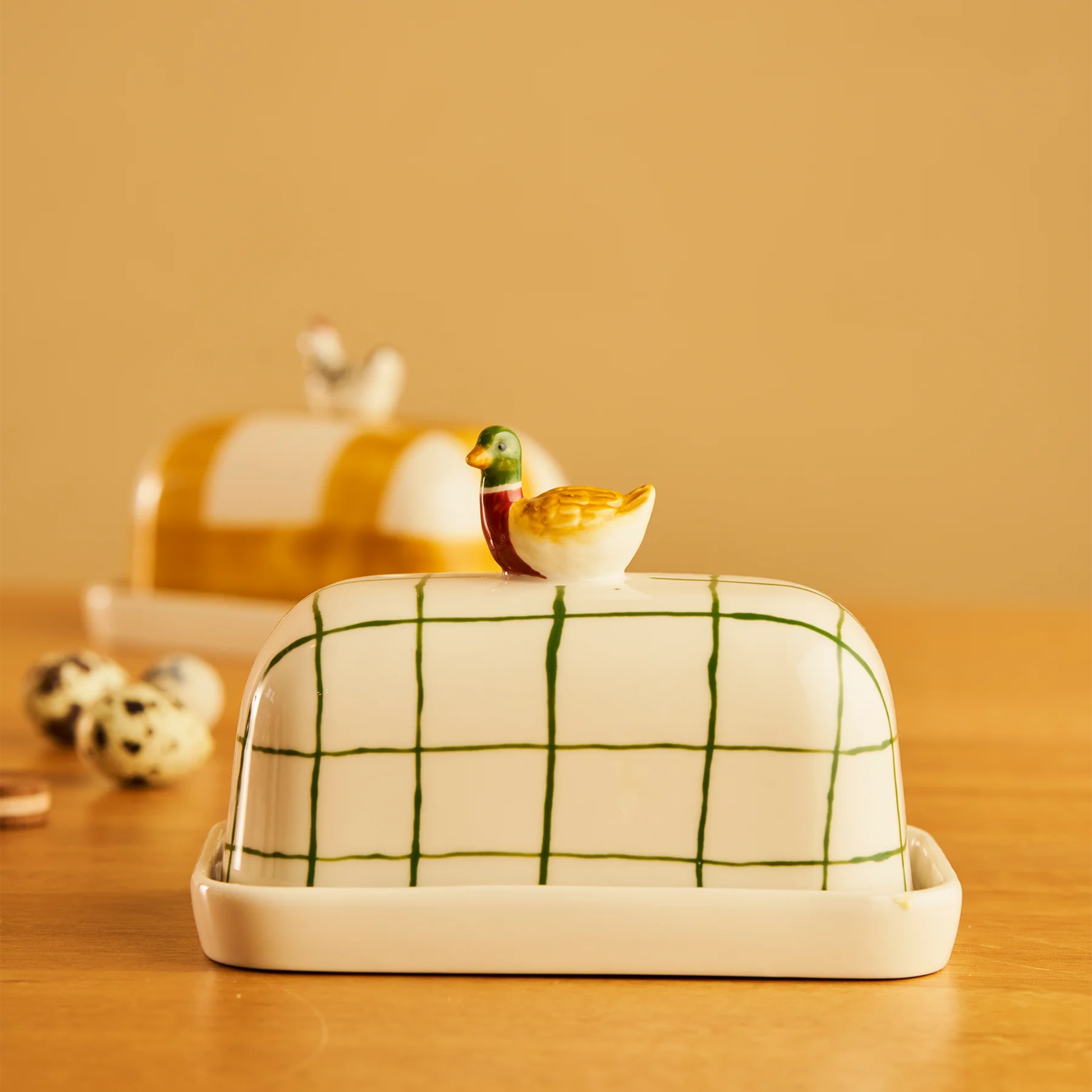 Side view of the Robert Gordon Butter Dish Duck made from high fired porcelain with green brushwork lines and a hand-painted duck perched on top.