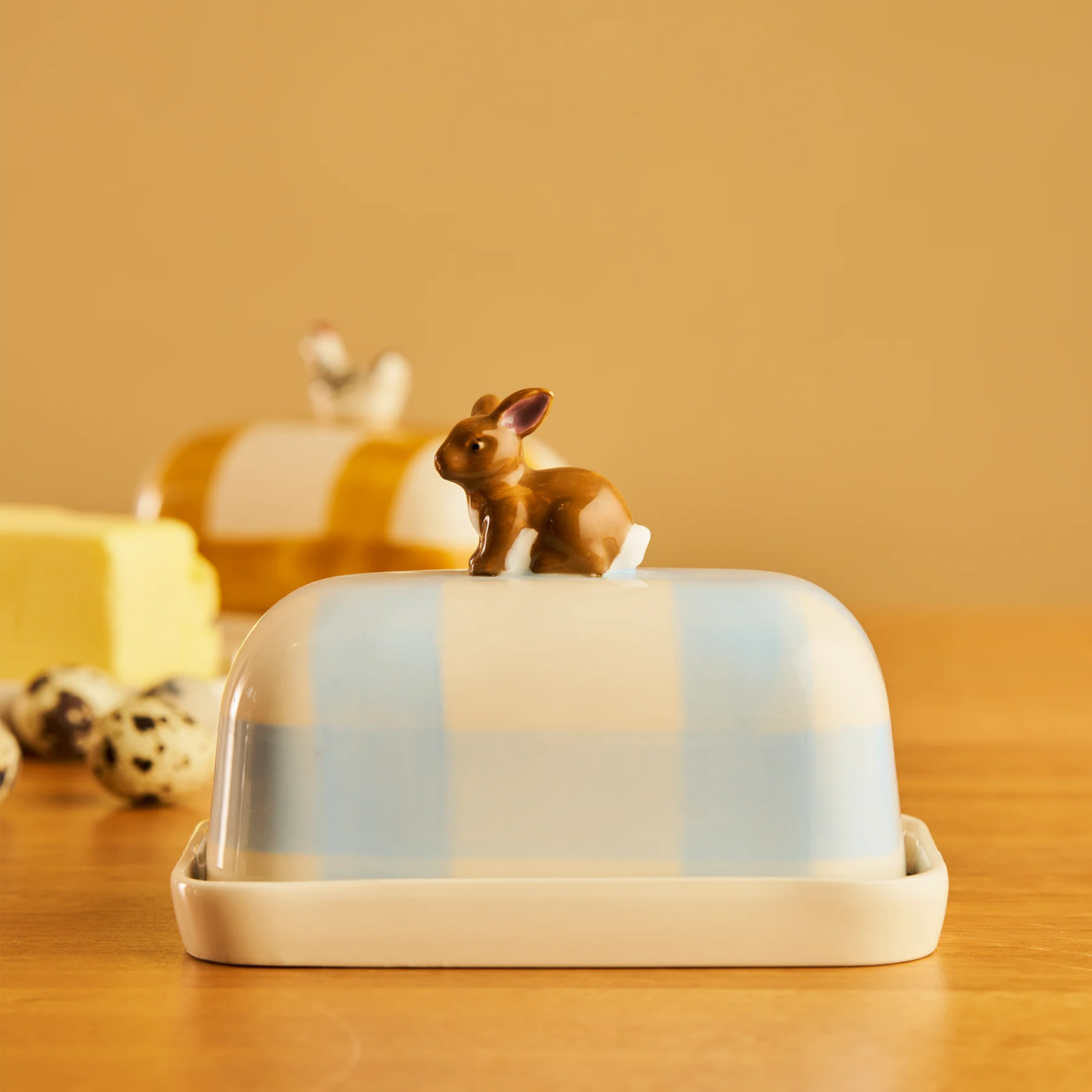 Side view of the Robert Gordon Butter Dish Rabbit made from high fired porcelain with blue brushwork lines and a hand-painted rabbit perched on top.