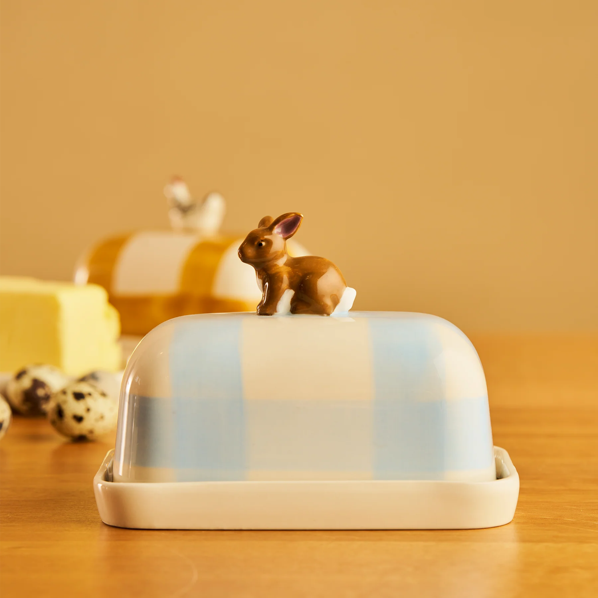 Side view of the Robert Gordon Butter Dish Rabbit made from high fired porcelain with blue brushwork lines and a hand-painted rabbit perched on top.