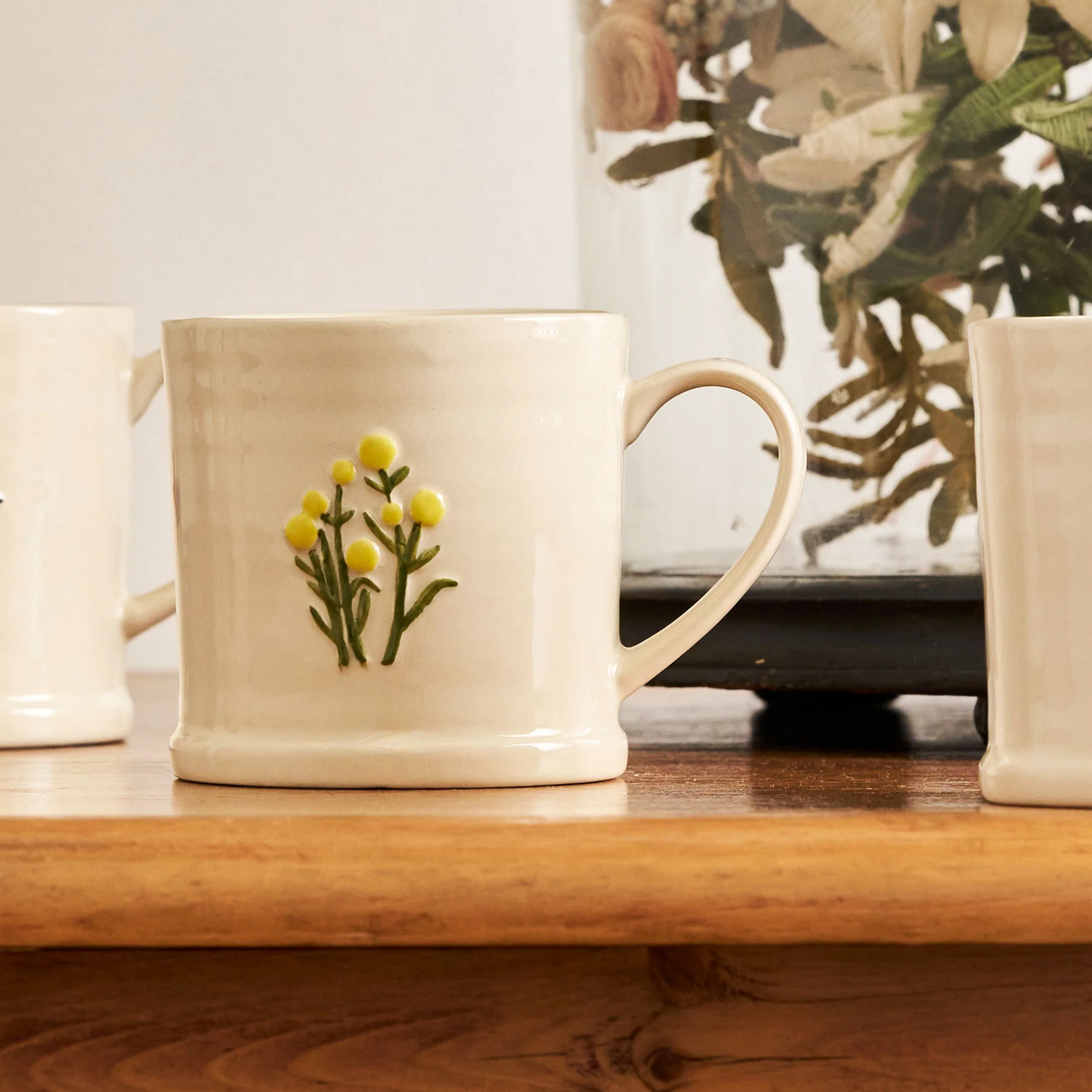On a wooden table, the Robert Gordon Favourite Things Mug Large featuring quirky hand painted Billy Button design.