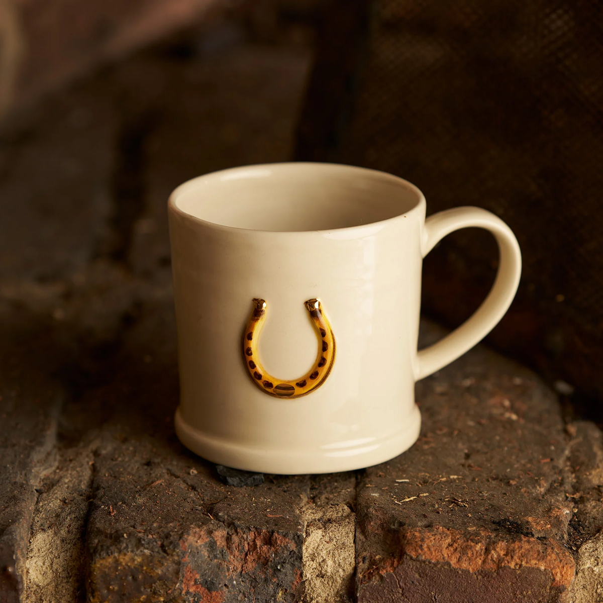 Front view of the Robert Gordon Favourite Things Mug Large on a brick, made from stoneware with Horse Shoe motif painted by hand with 310ml capacity.