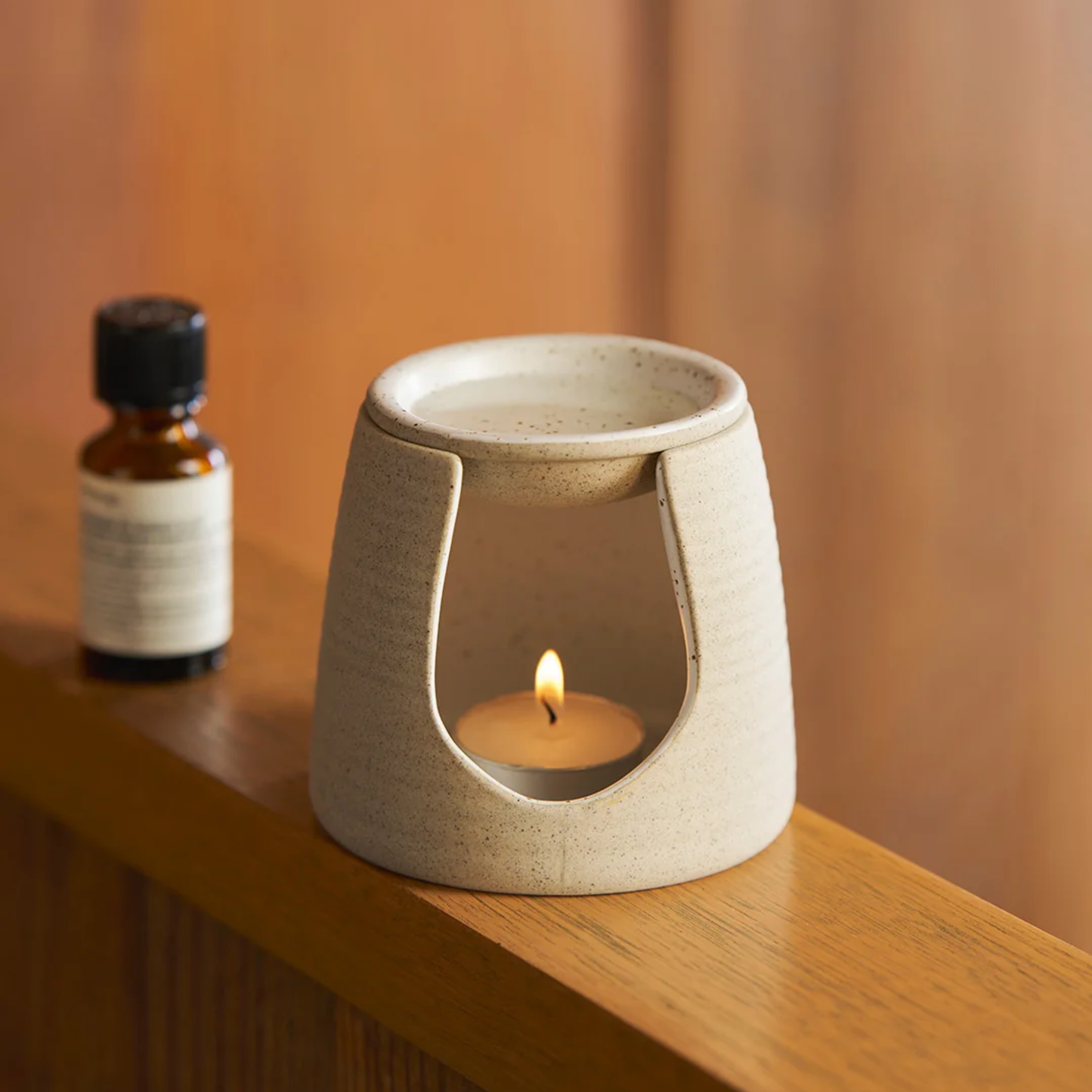 Front view of the Robert Gordon Garden To Table Oil Burner that is made from durable stoneware with candle inside.