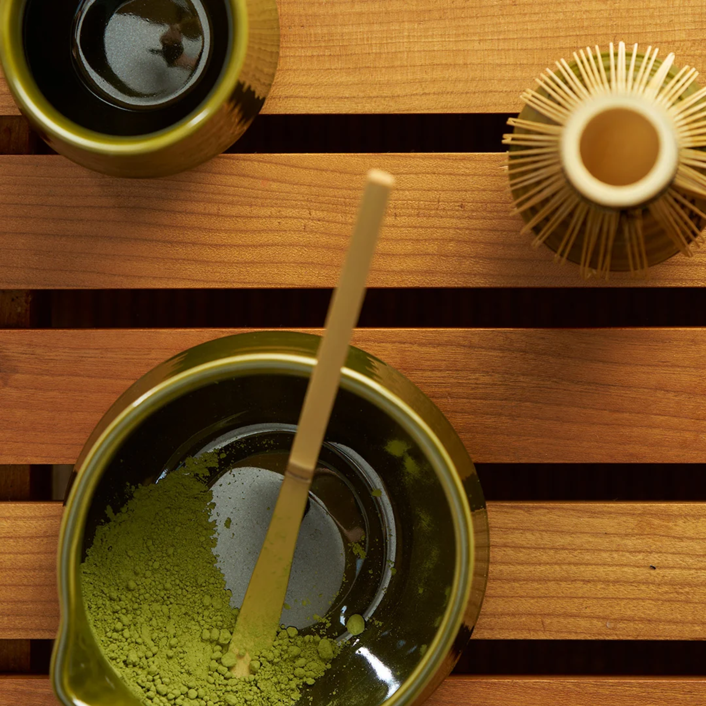 On the table are the Robert Gordon Matcha 4 Piece Set Matcha for traditional ceremonial matcha which are the ceramic bowl, whisk holder and bamboo whisk and scoop.