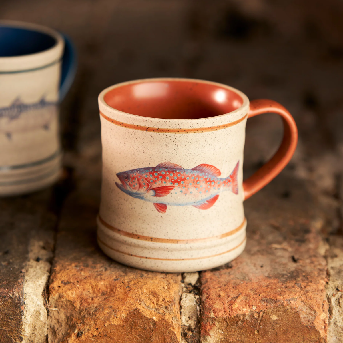Robert Gordon Mug on top of the bricks featuring Australian artist Michelle Turner's Trout illustration for a nostalgic coastal holidays.