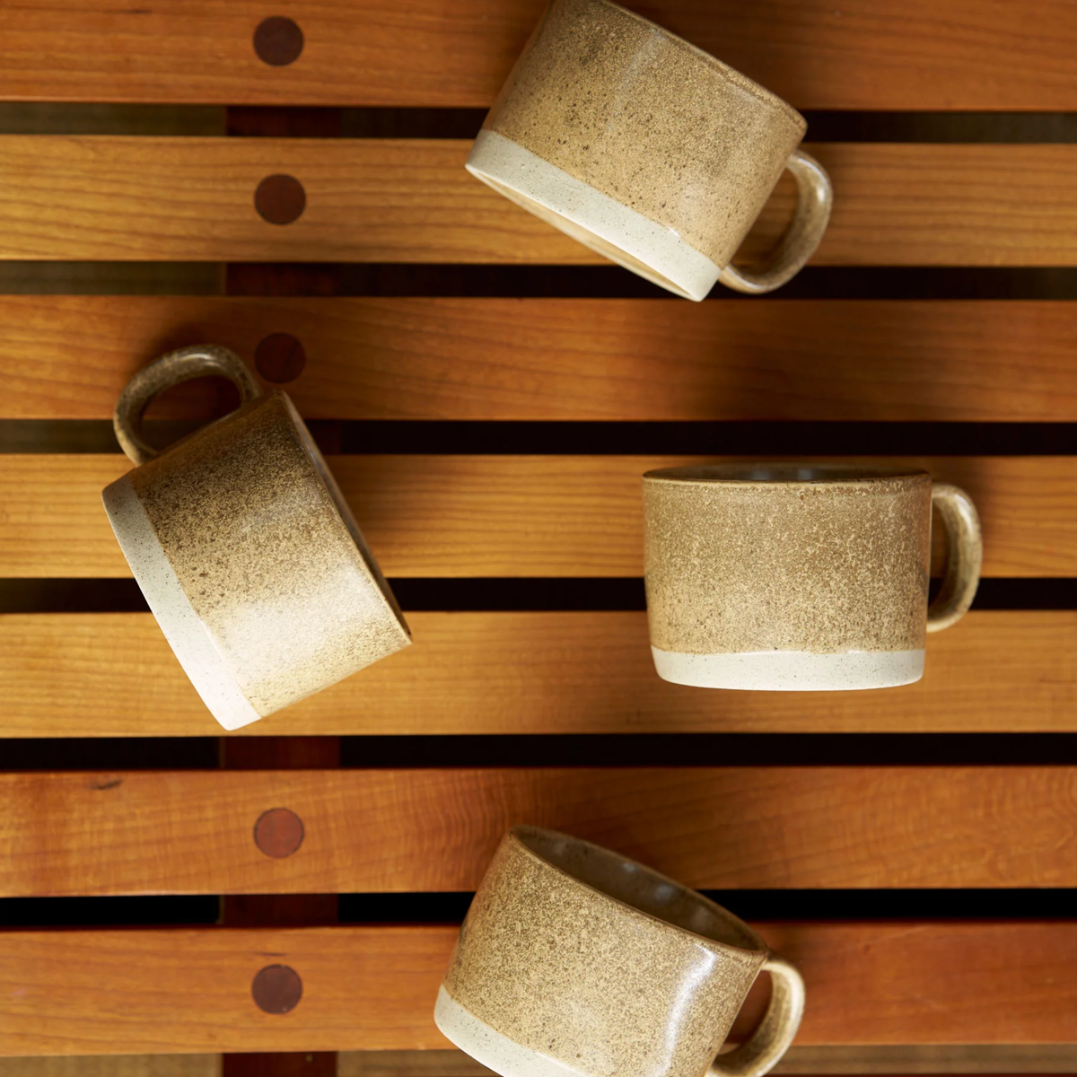 Side view of the Robert Gordon Mineral Mugs (set of 4) Zircon on a wood surface, featuring its reactive glaze finish over an earthly clay body durable stoneware.