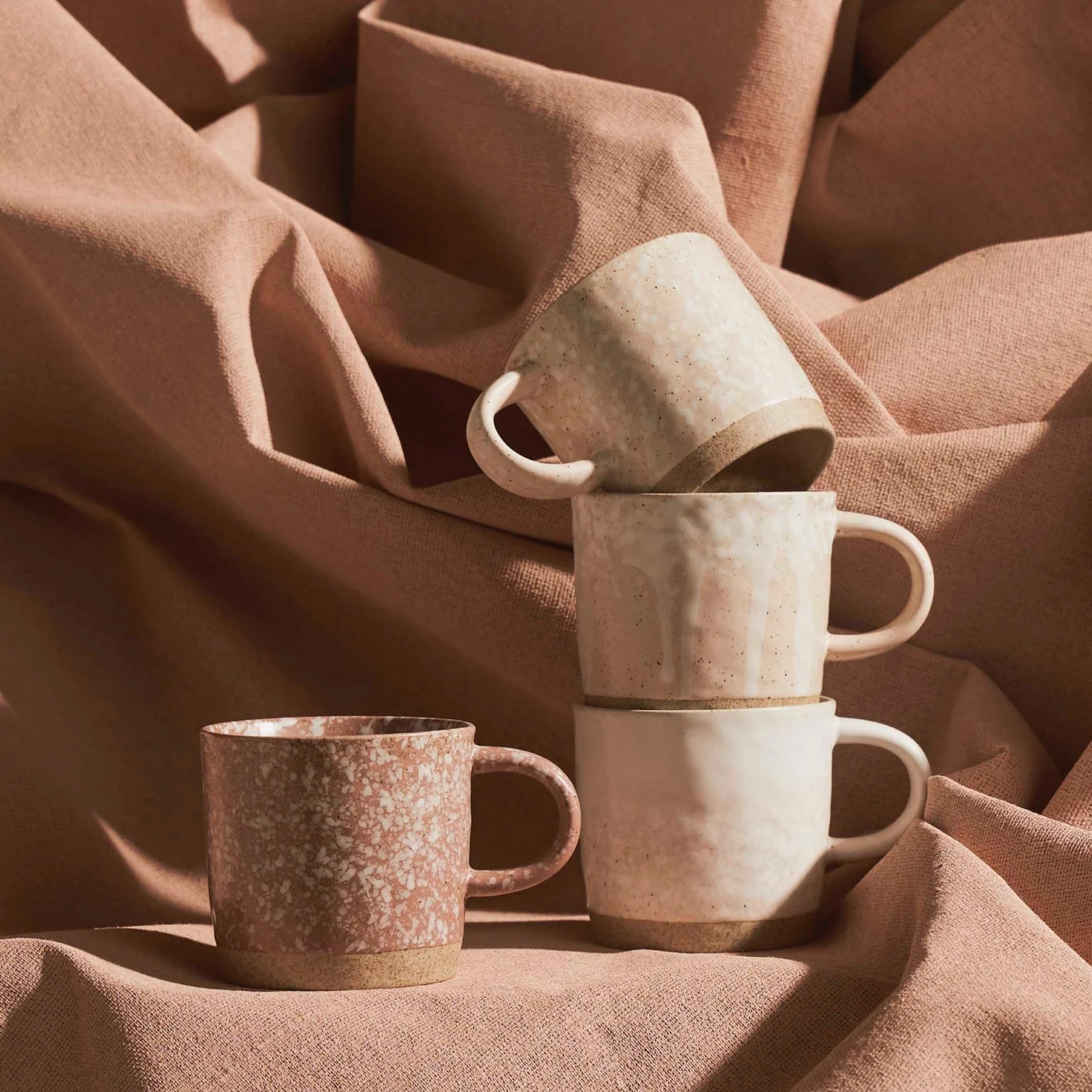 Robert Gordon set of 4 stoneware pink mugs stacked on folded linen background