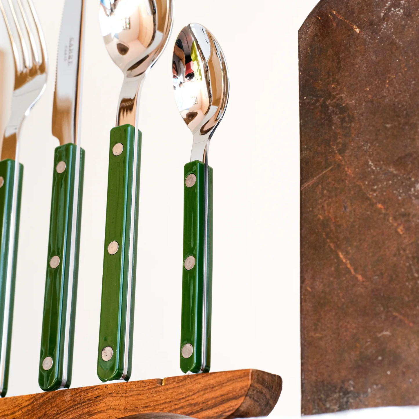 Close up on the spoon, knife, fork and teaspoon standing on a wooden clip, from Sabre Bistrot Cutlery Dark Green 24 Piece Set