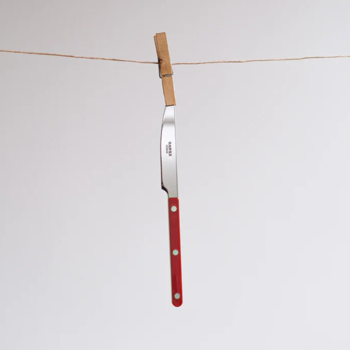 Being hung on a wire using a clip Sabre Paris Bistrot Dinner Knife Burgundy - 24cm stainless steel knife with colorful nylon handle and visible rivets. Designed with a sharp elegant blade inspired by French cafés, this durable and stylish dinner knife is available in gloss or vintage finishes and dishwasher-safe.