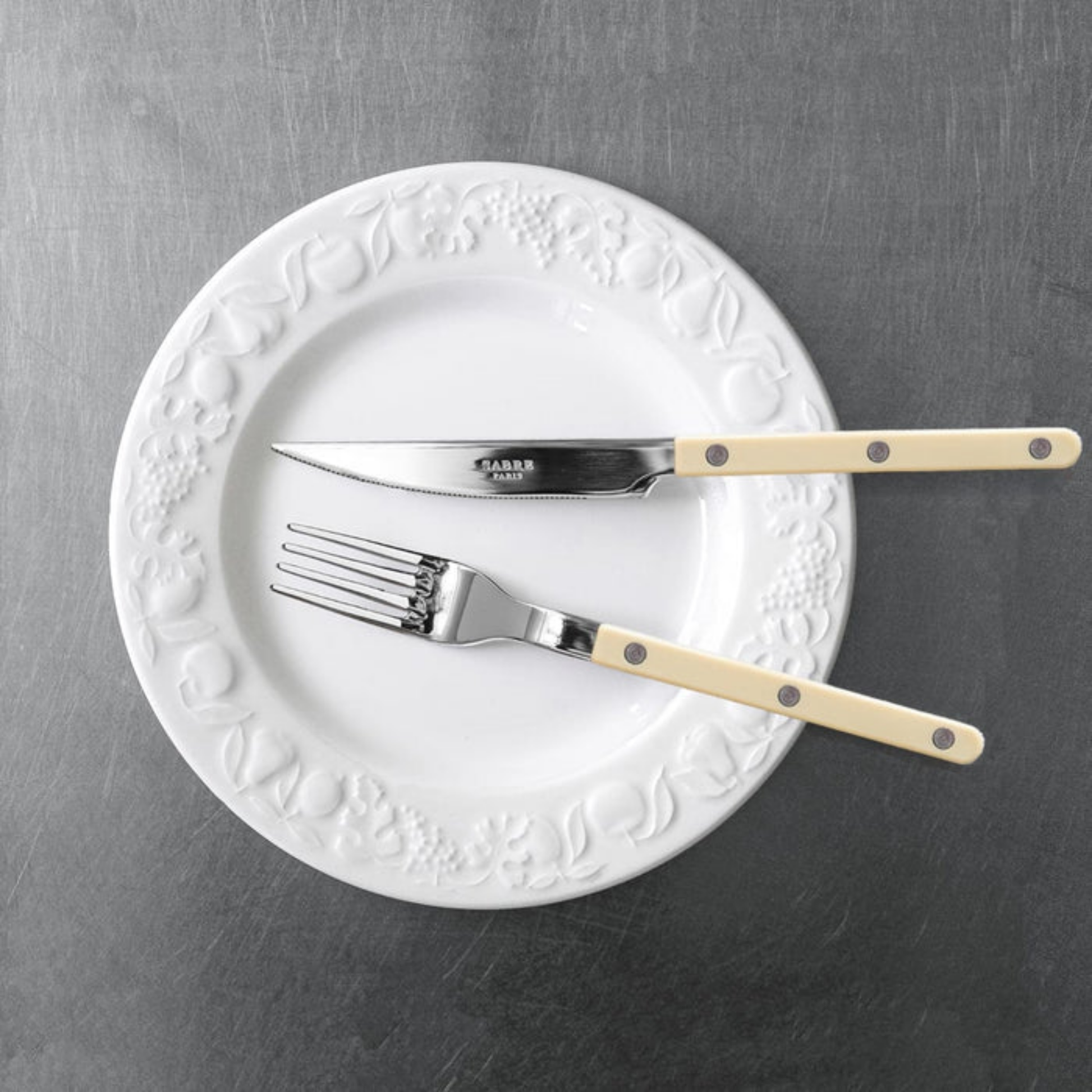 Shown on a plate with a fork Sabre Paris Bistrot Dinner Knife 24 cm Ivory - stainless steel and nylon cutlery inspired by French cafés, featuring visible rivets, sharp blade, and gloss or vintage finish for stylish table settings.