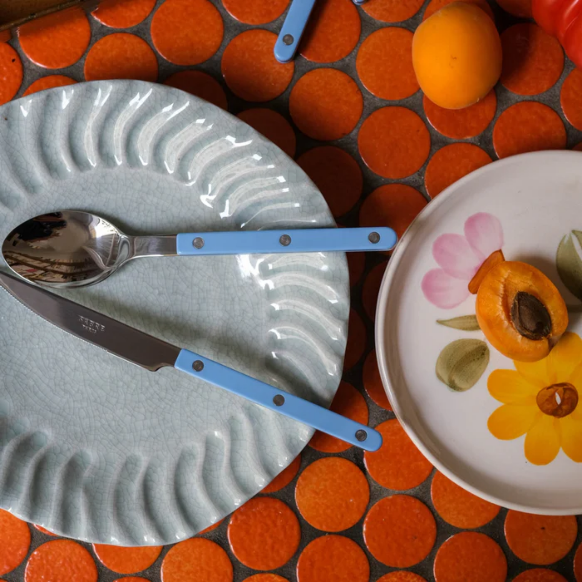 On a plate with a spoon Sabre Paris Bistrot Dinner Knife Pastel blue- 24cm stainless steel knife with colorful nylon handle and visible rivets. Features a sharp blade for elegant dining, inspired by classic French bistros with a modern touch. Dishwasher-safe, available in gloss or vintage finishes.