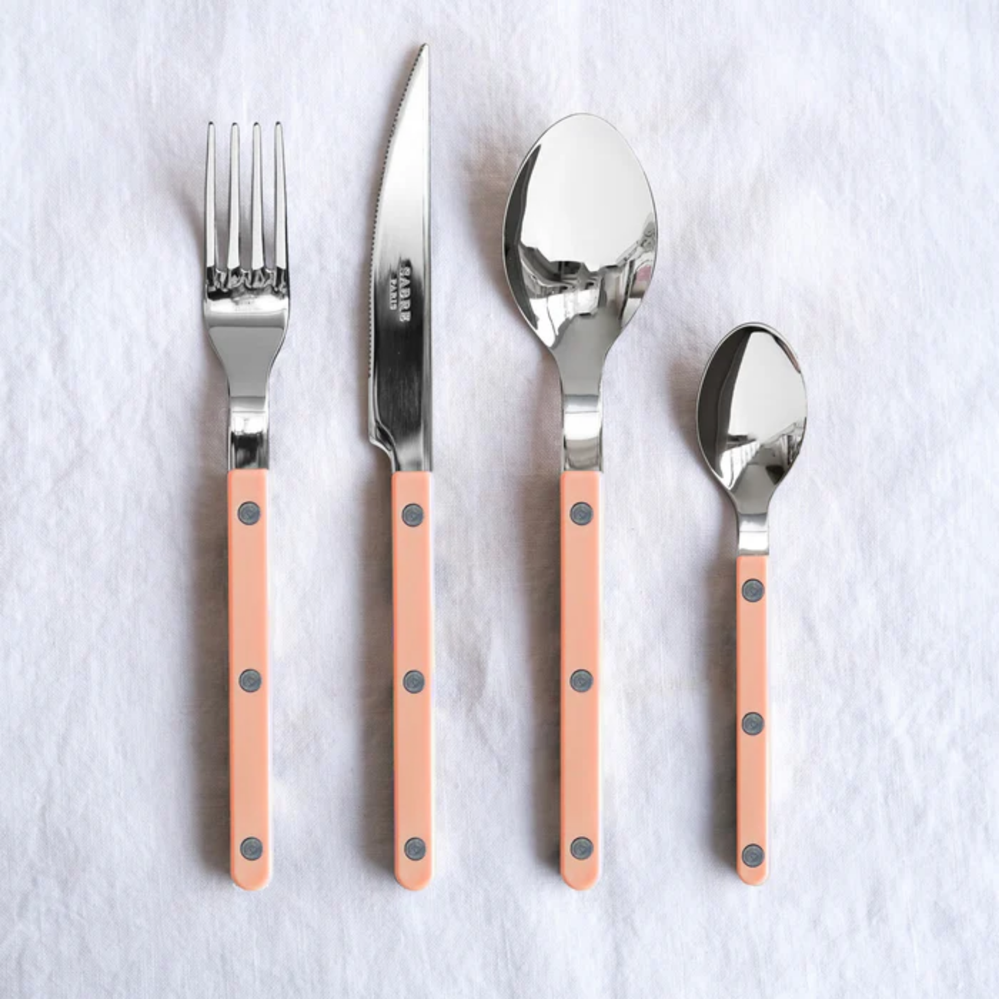 Shown with other bigger utensils for comparison Sabre Paris Bistrot Teaspoon nude pink- 16cm stainless steel teaspoon with durable nylon handle and riveted bistro design. Elegant, dishwasher-safe cutlery blending traditional charm with modern style.