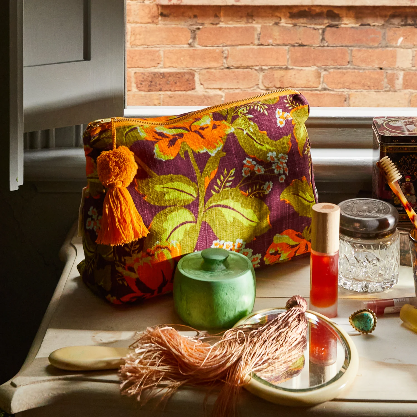 Upclose view on a cabinet Sage and Clare organic cotton cosmetic bag Margot with wide zip opening, tassel detail, and water-resistant lining - ideal for travel beauty essentials.