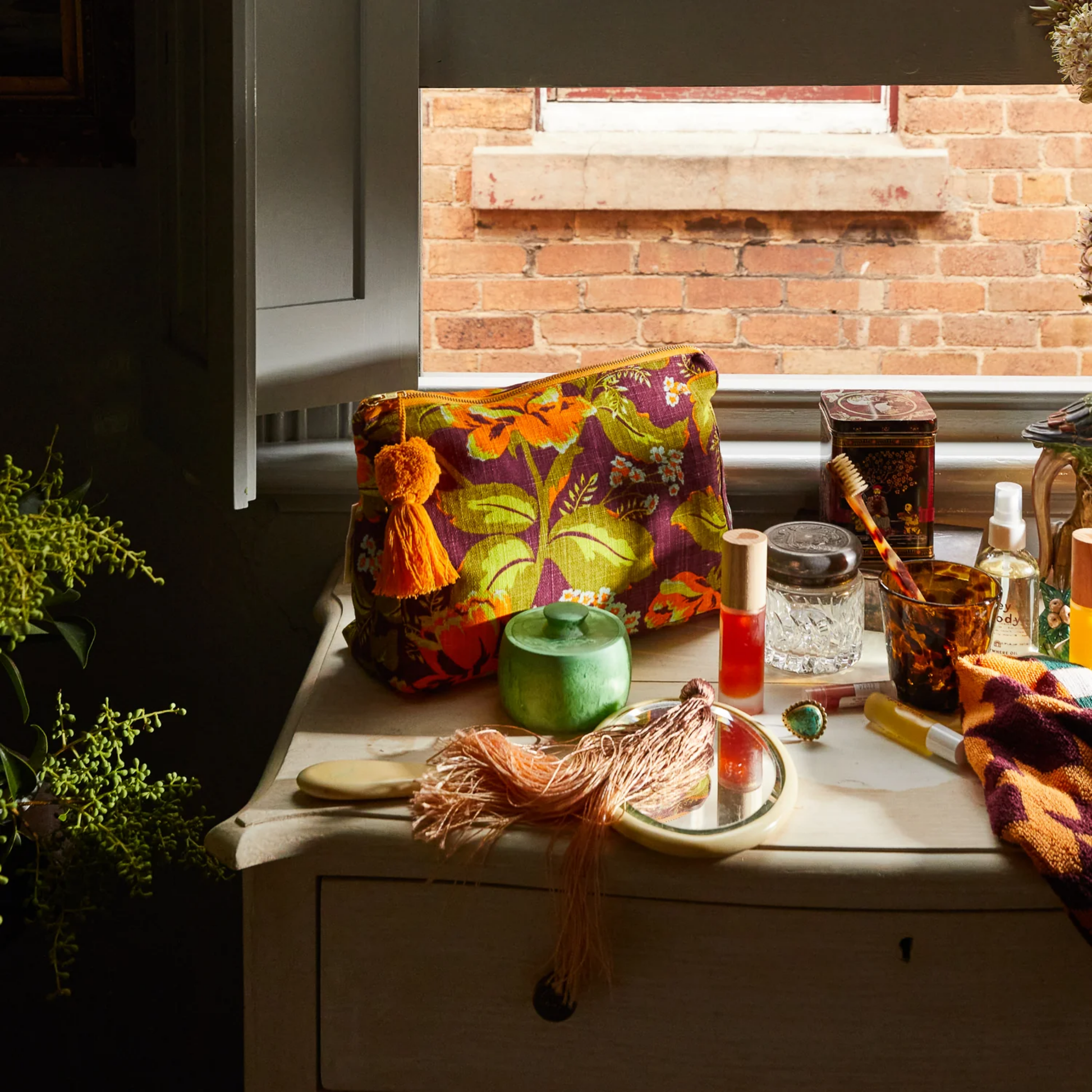 Shown on a cabinet Sage and Clare organic cotton cosmetic bag Margot with wide zip opening, tassel detail, and water-resistant lining - ideal for travel beauty essentials.