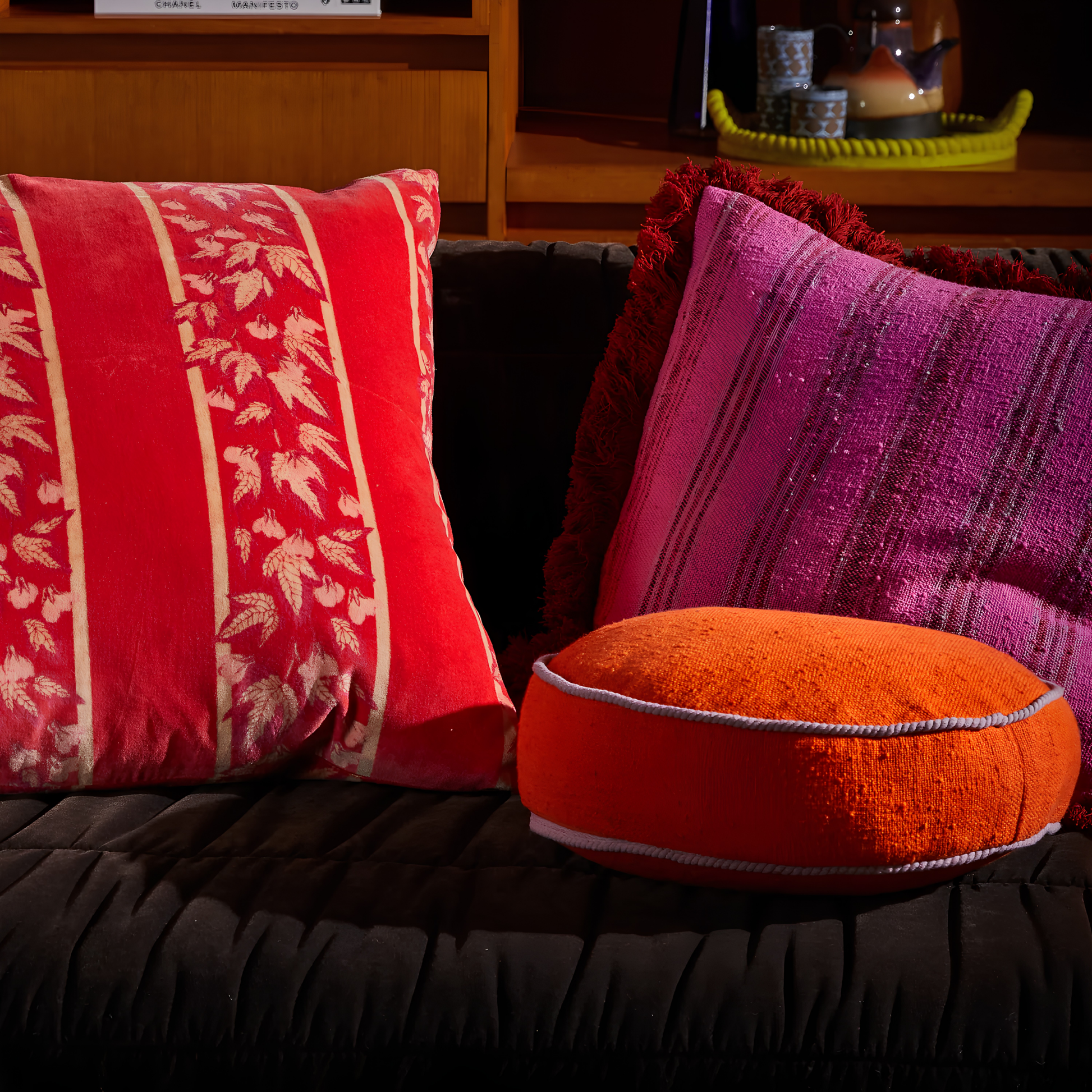 On a couch with other square pillows, the Sage & Clare Cushion Dana Round Orangerie made from cotton in block colours, with contrasting cord piping and high quality insert.