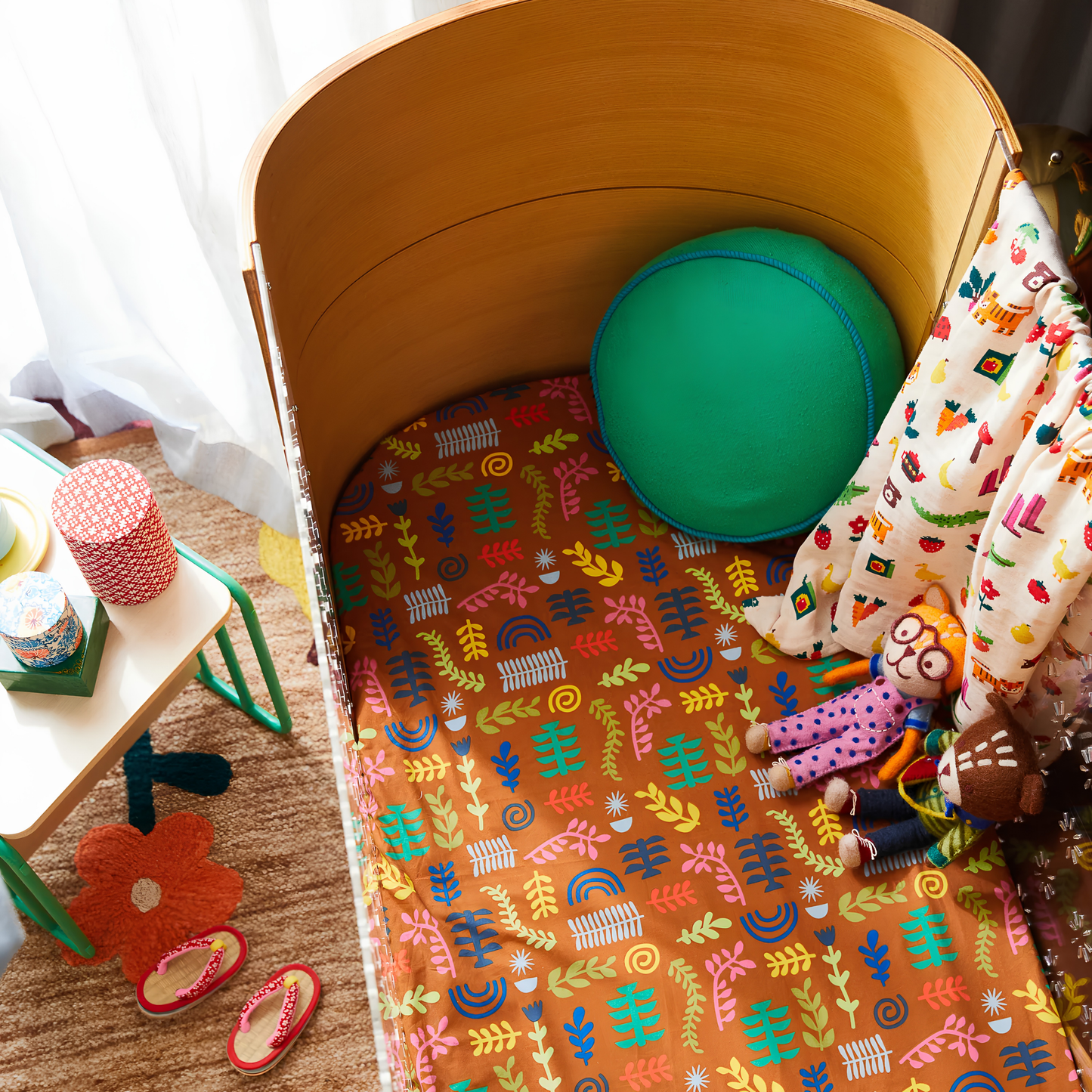 Leaning in the side of the baby's crib, the Sage & Clare Cushion Dana Round Spring Green made from cotton in block colours, with contrasting cord piping and high quality insert.