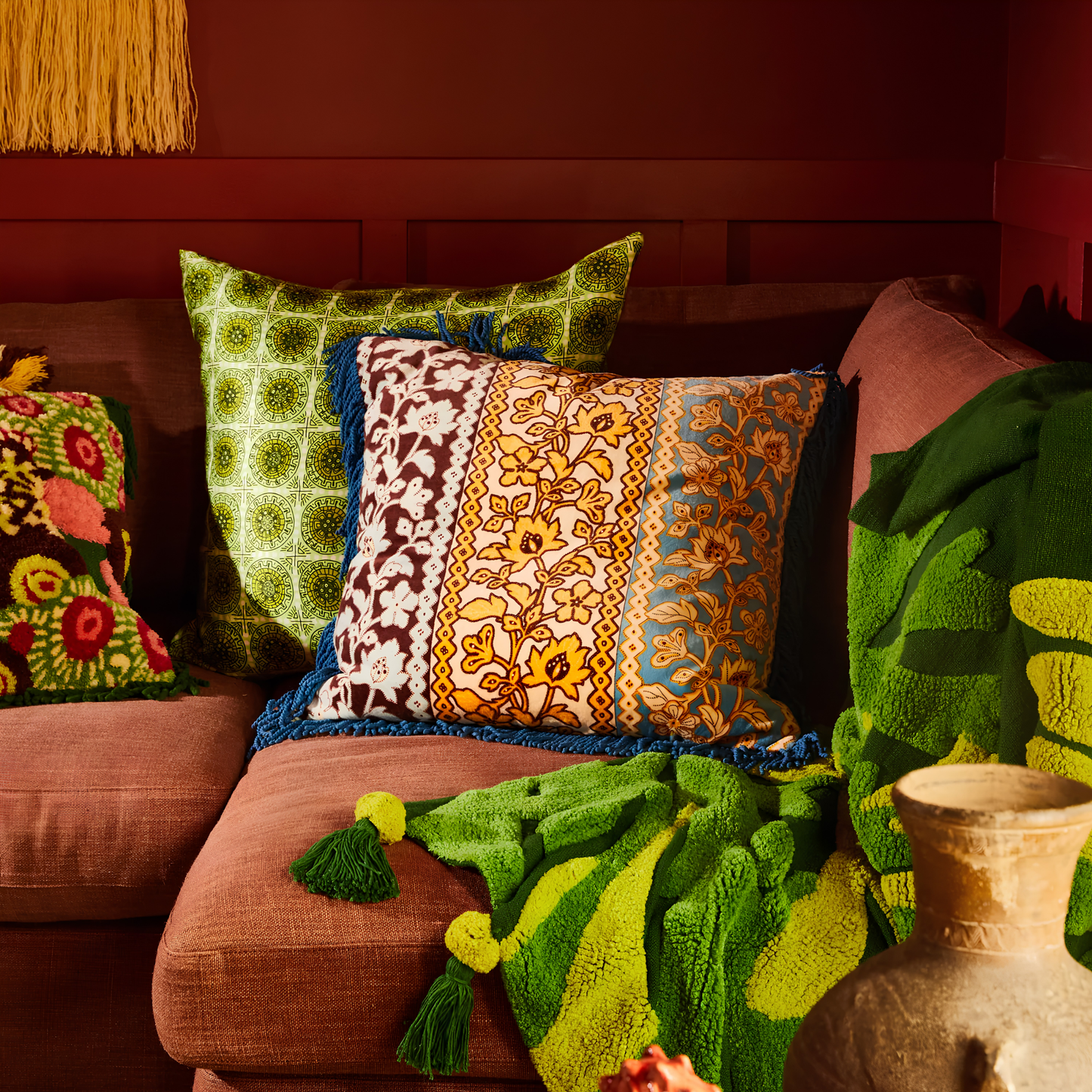Sage & Clare Cushion Thea Velvet Azure with plush texture, floral design, fringe edges and high quality insert, leaning on a couch.
