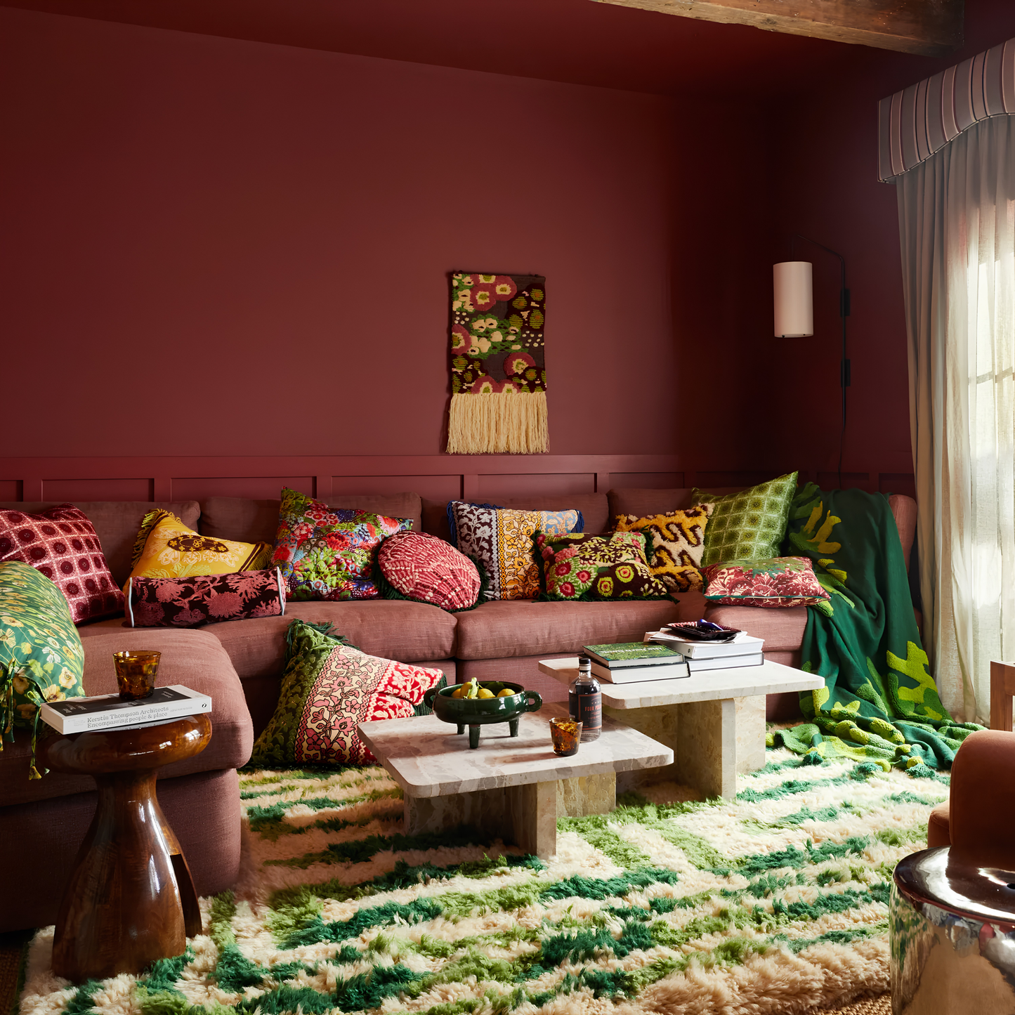 Wide angle view on a couch with other pillows, the Sage & Clare Cushion Thea Velvet Azure with plush texture, floral design, fringe edges and high quality insert.