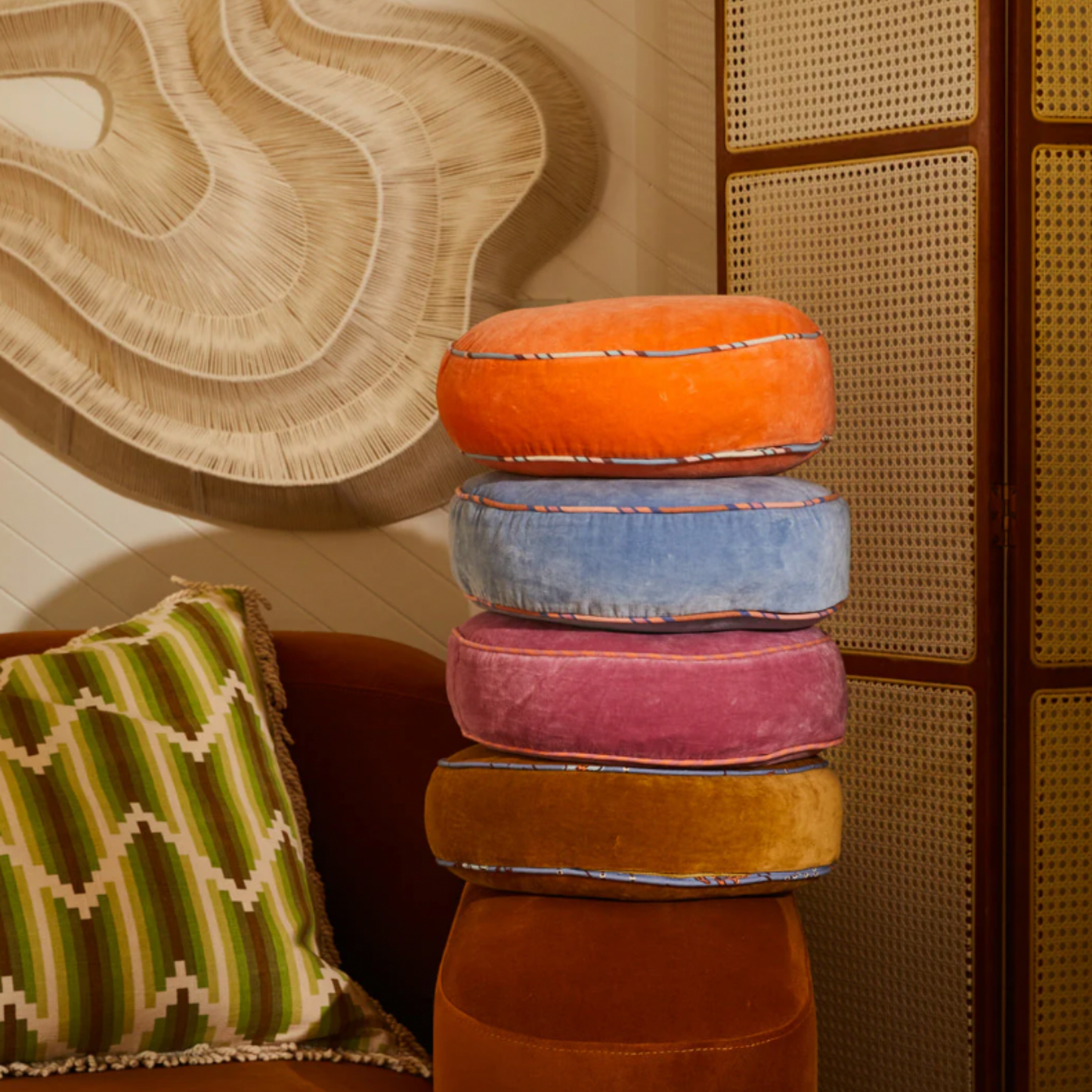 Sage & Clare Velvet Castillo round desert cushion stacked on arm of couch with other Velvet Castillo round cushion