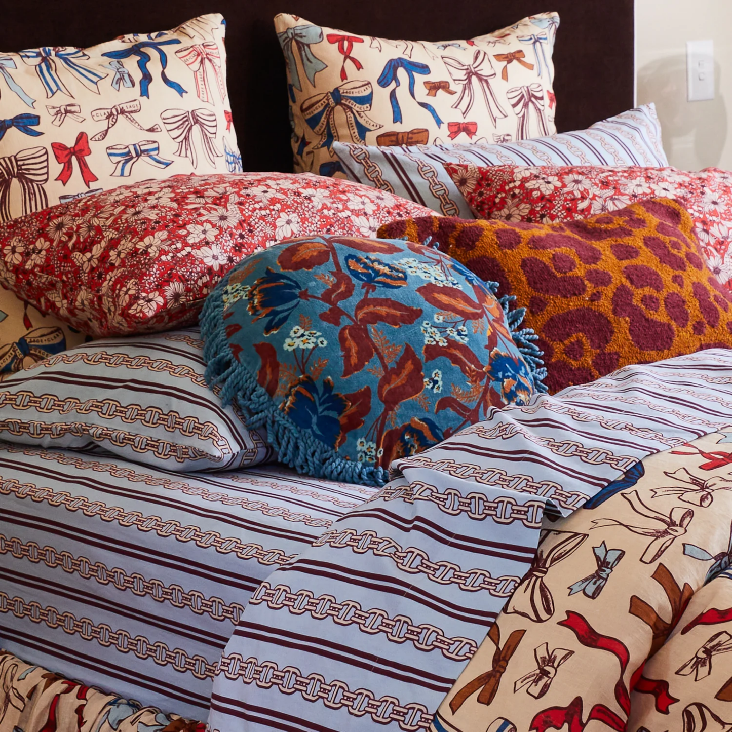 In bed setting with other pillows Sage x Clare Velvet Margot Celeste round velvet cushion featuring a soft-touch plush velvet front, cotton reverse, and fringe edges - includes premium feather or vegan insert for a super-soft, luxurious feel.