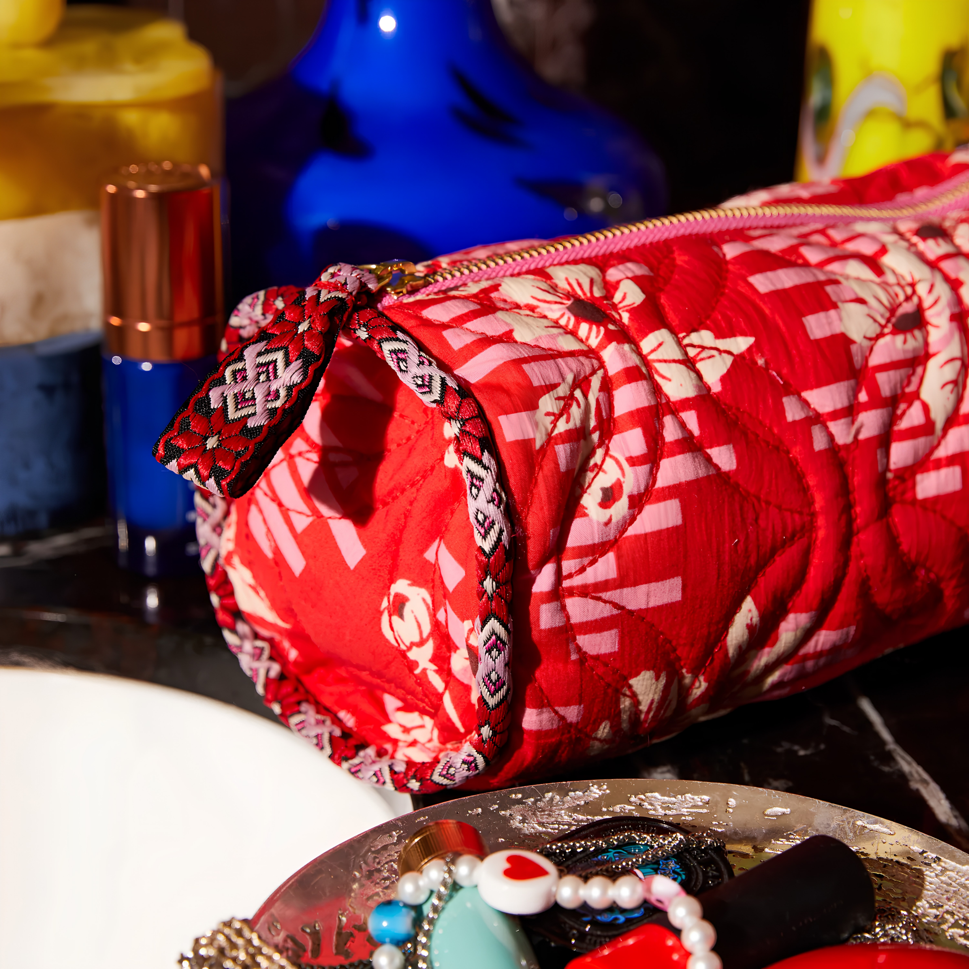 Close up on the Sage & Clare Makeup Bag Marta Vermillion round and roomy with wide zip opening, lightly quilted and a compact design on a vanity countertop.\