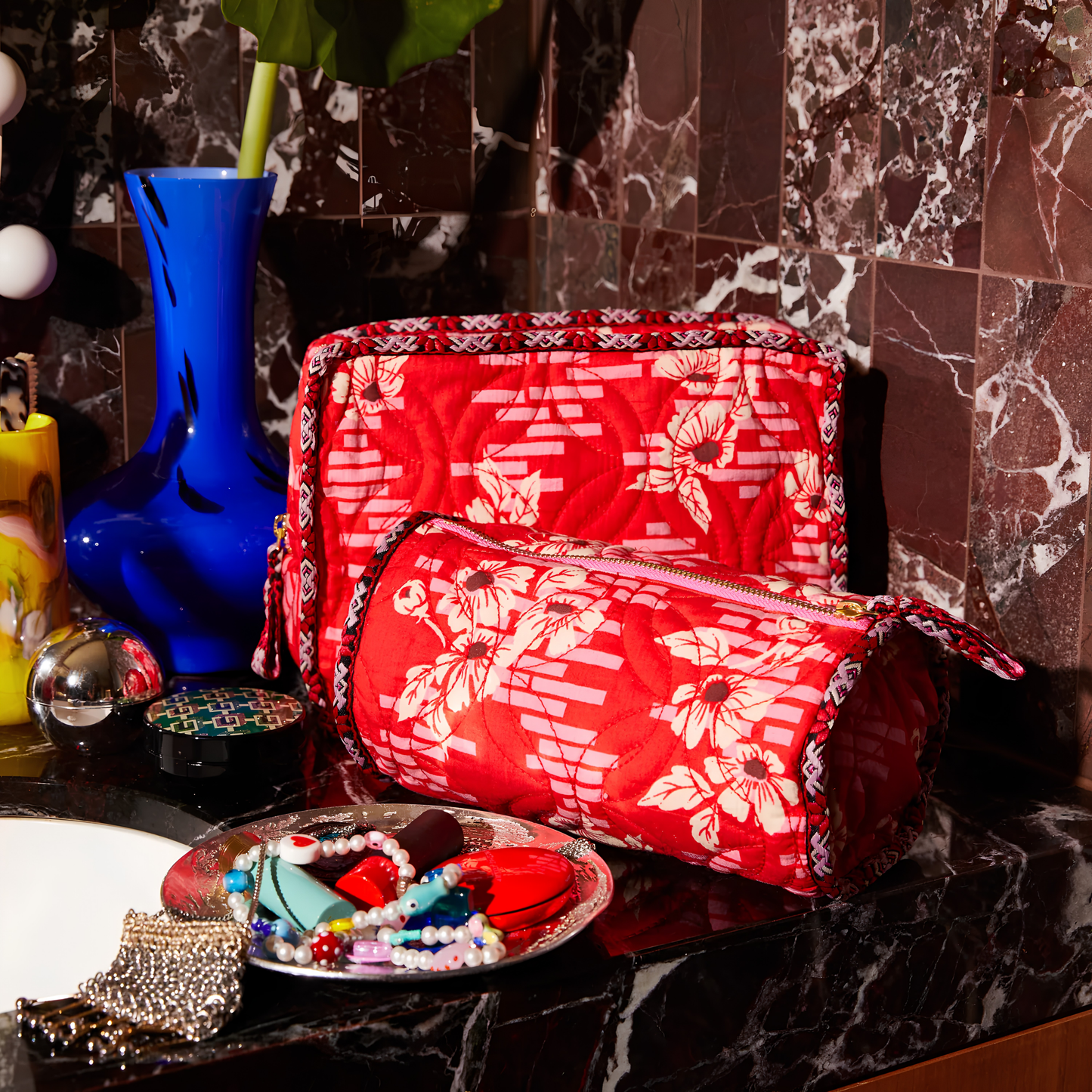 Sage & Clare Makeup Bag Marta Vermillion round and roomy with wide zip opening, lightly quilted and a compact design, on the vanity countertop with the Marta vanity bag.