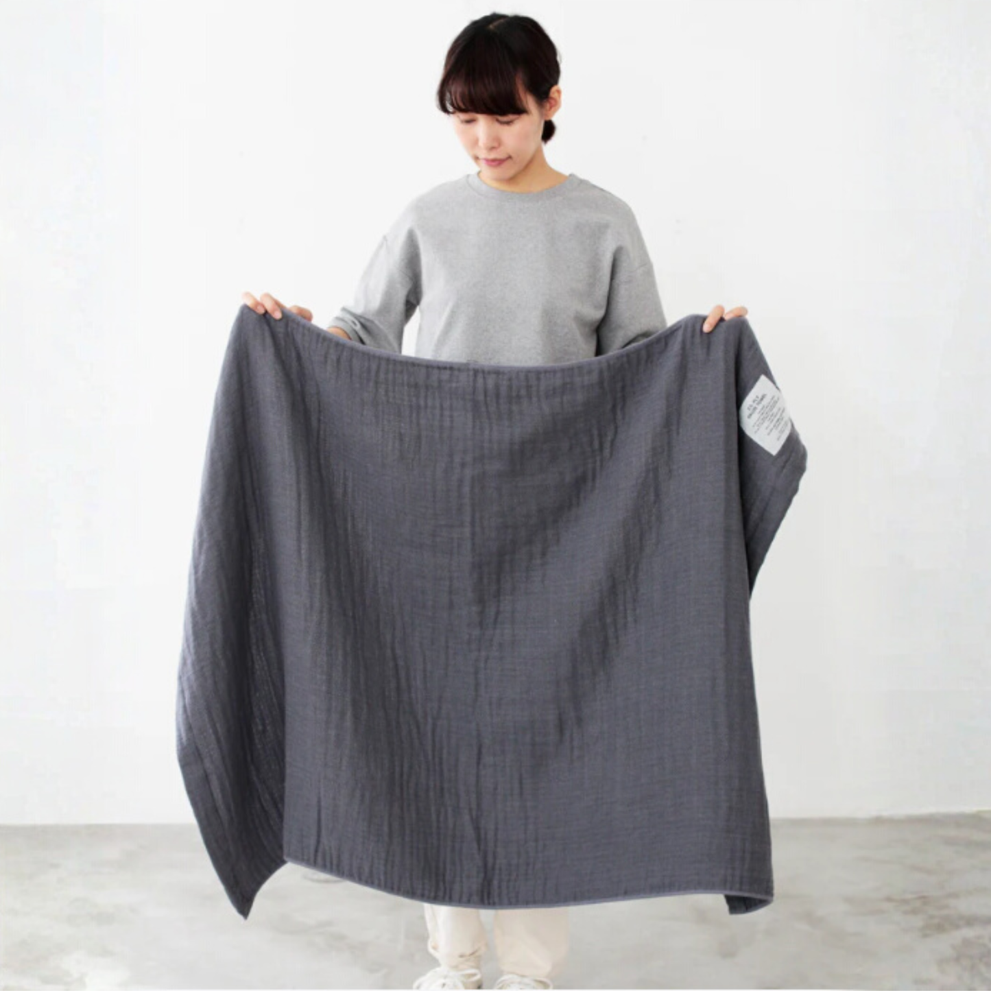 Shown being held open arms by a woman Shinto 2.5 Ply Gauze Bath Towel - Charcoal, 100% organic cotton, large 140x88cm, soft, fast-drying, feather-light, highly absorbent, Japanese-made.