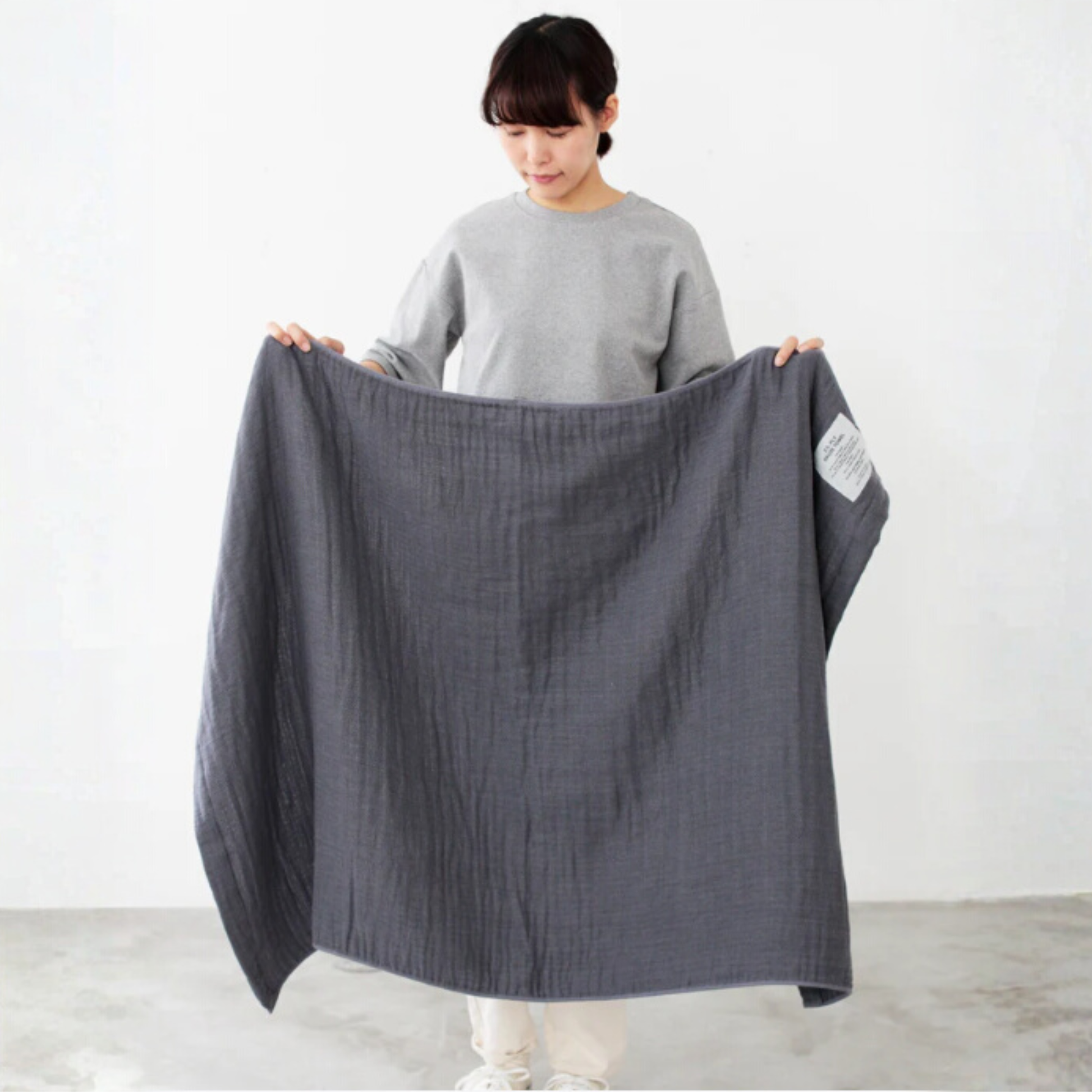 Shown being held open arms by a woman Shinto 2.5 Ply Gauze Bath Towel - Charcoal, 100% organic cotton, large 140x88cm, soft, fast-drying, feather-light, highly absorbent, Japanese-made.