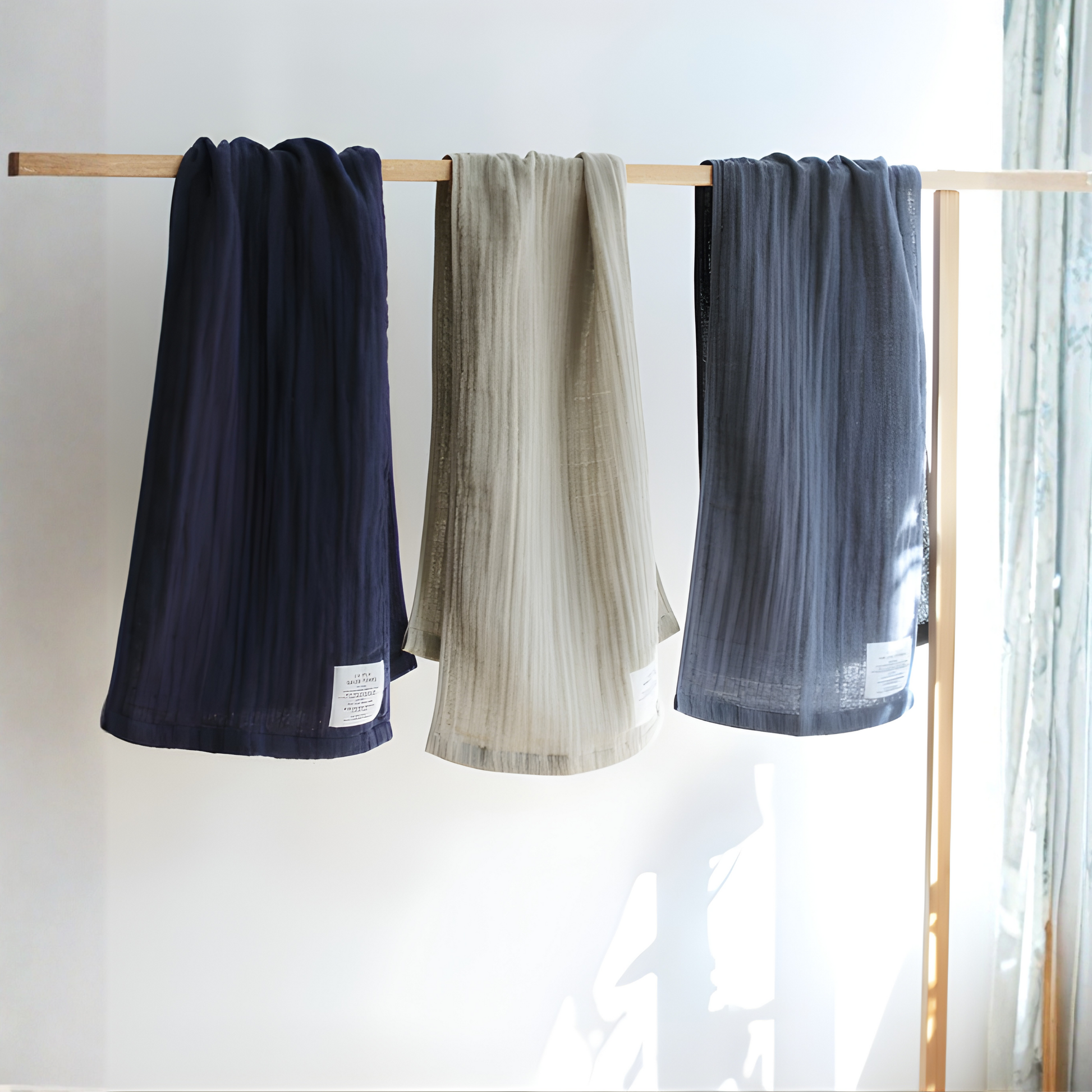 Showing Shinto 2.5 Ply Gauze Hand Towel - Charcoal, being hung on the right with other colors, 100% organic cotton, long 115x30cm, soft, fast-drying, feather-light, highly absorbent, Japanese-made.
