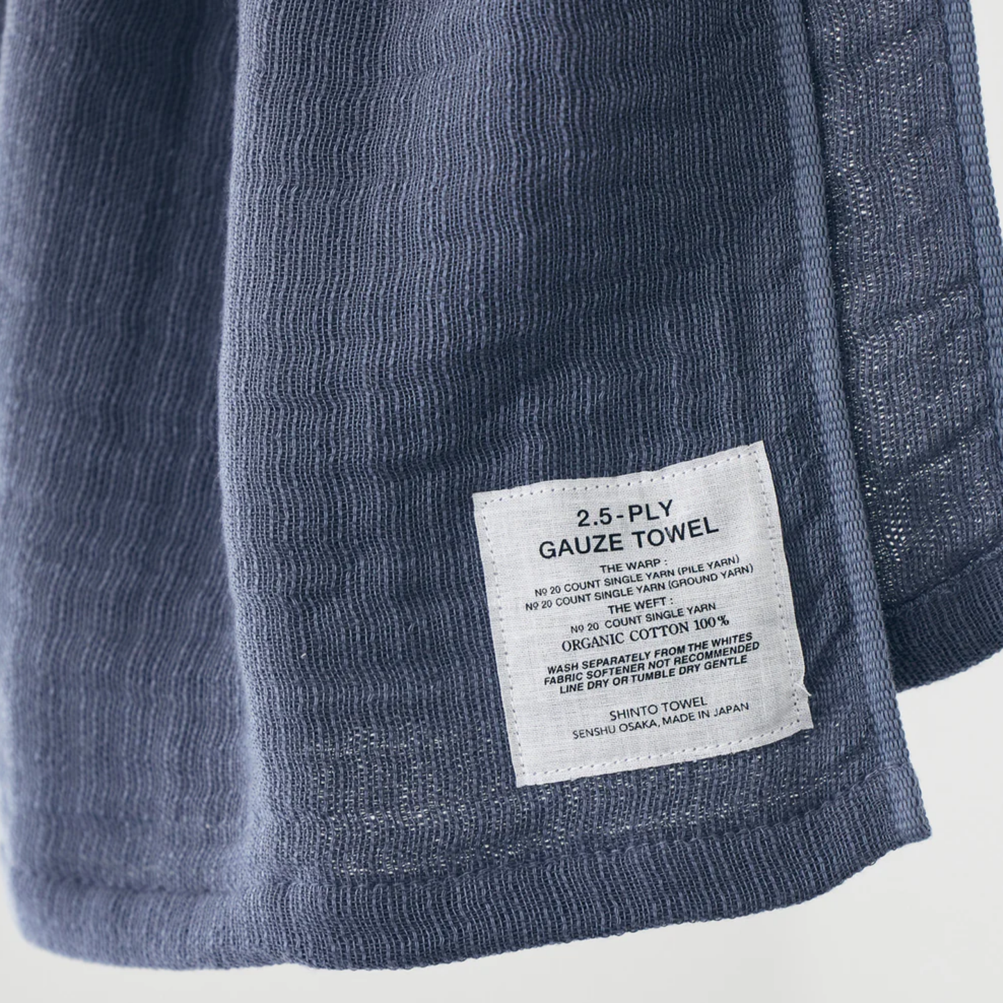 Close up with the tag of Shinto 2.5-Ply Gauze Wash Cloth Charcoal - organic cotton towel, 30x34cm, lightweight and highly absorbent with soft layered weave for gentle, quick-drying comfort, made in Japan.