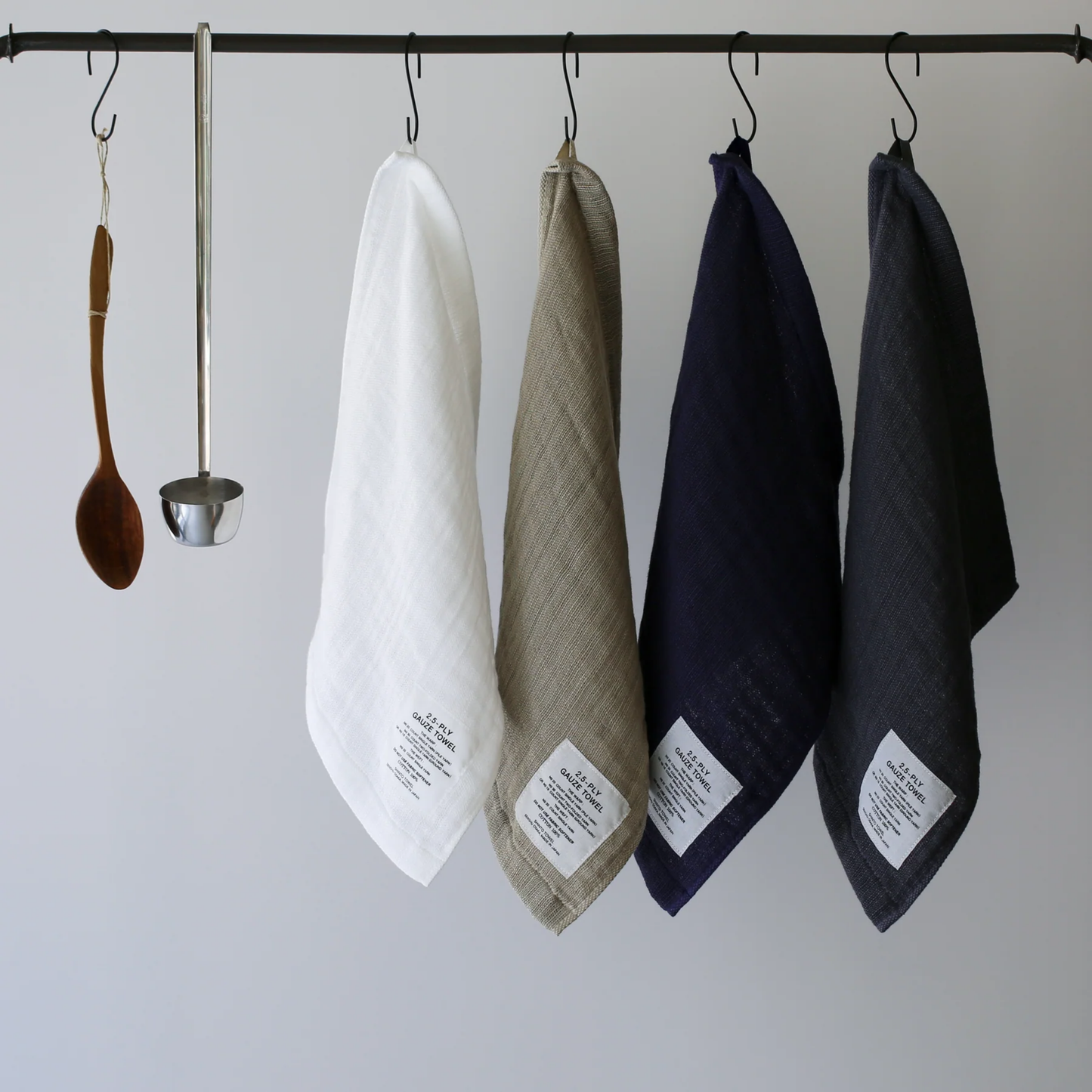 Shown being hung in the second to the last to the right with different other color Shinto 2.5-Ply Gauze Wash Cloth - Navy organic cotton towel, 30x34cm, lightweight and highly absorbent with soft layered weave for gentle, quick-drying comfort, made in Japan.