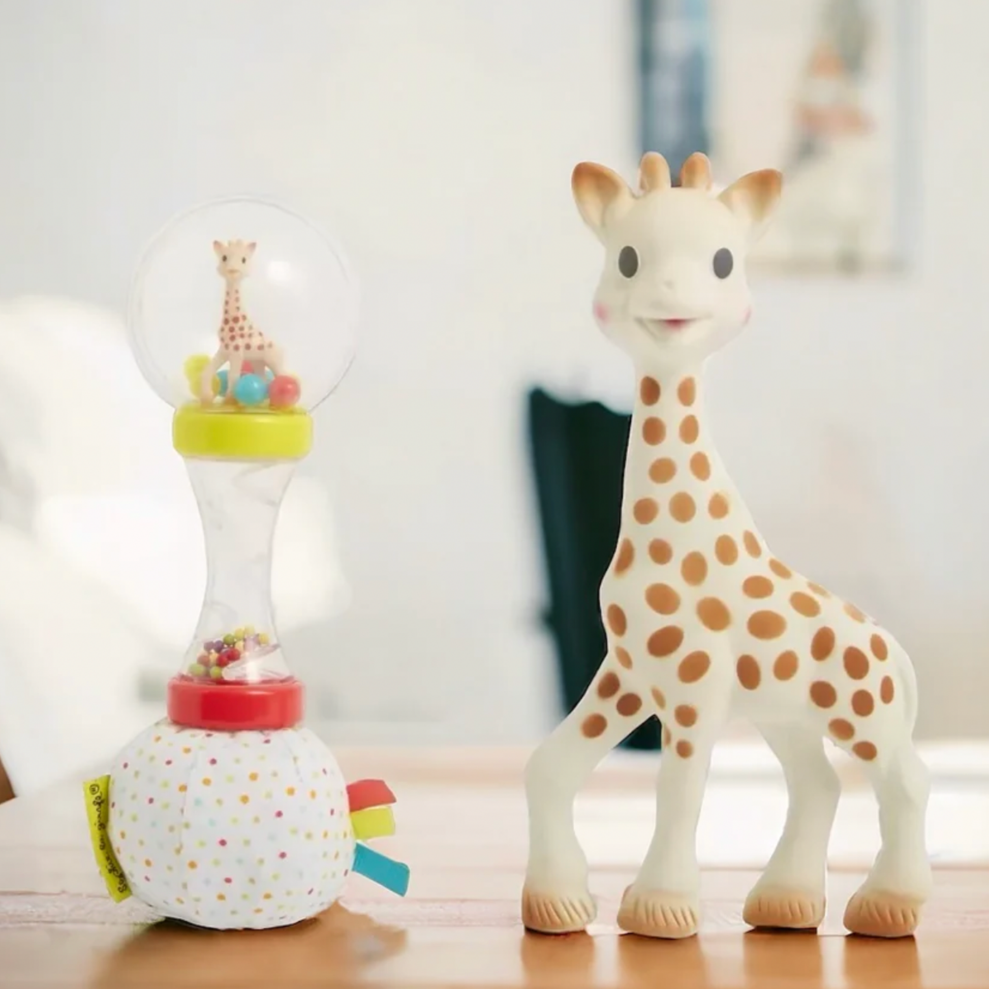 Sophie La Girafe rattle and girafe toy on wooden table in living room