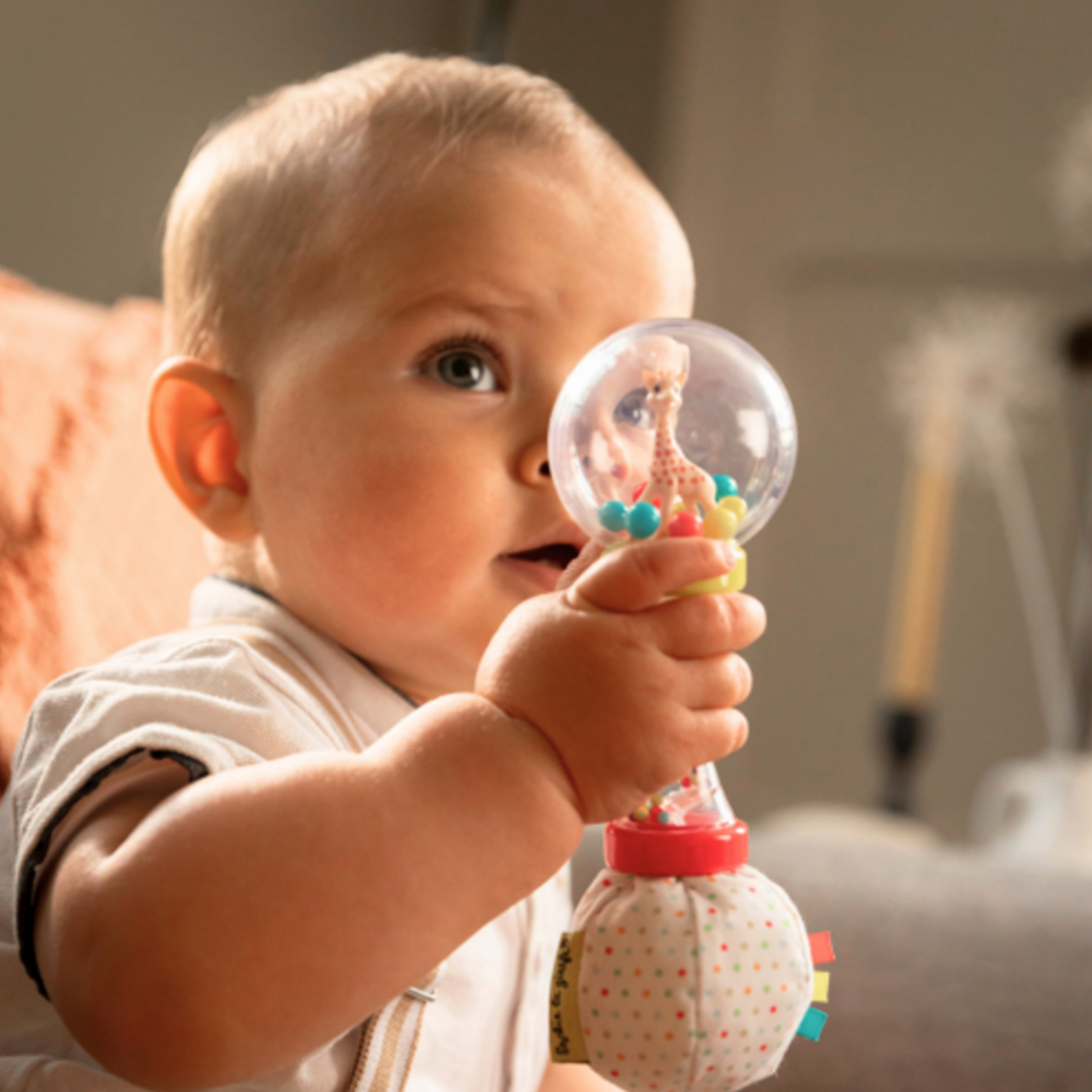 Baby playing with maracus rattle on couch close up