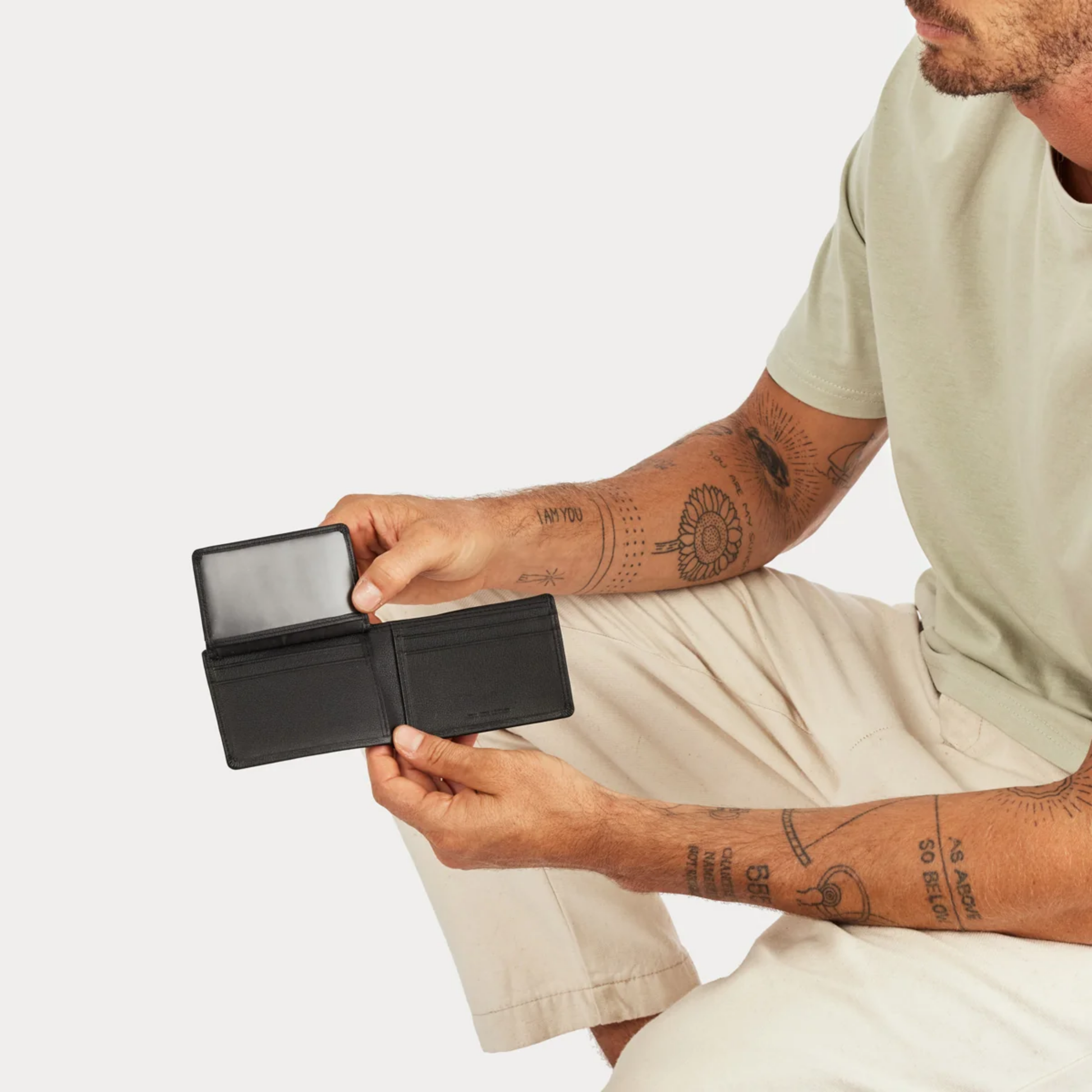 Open Status Anxiety Wallet Jonah Black from premium Italian leather with 6 card slots, and fits AUD & USD, held by a man.
