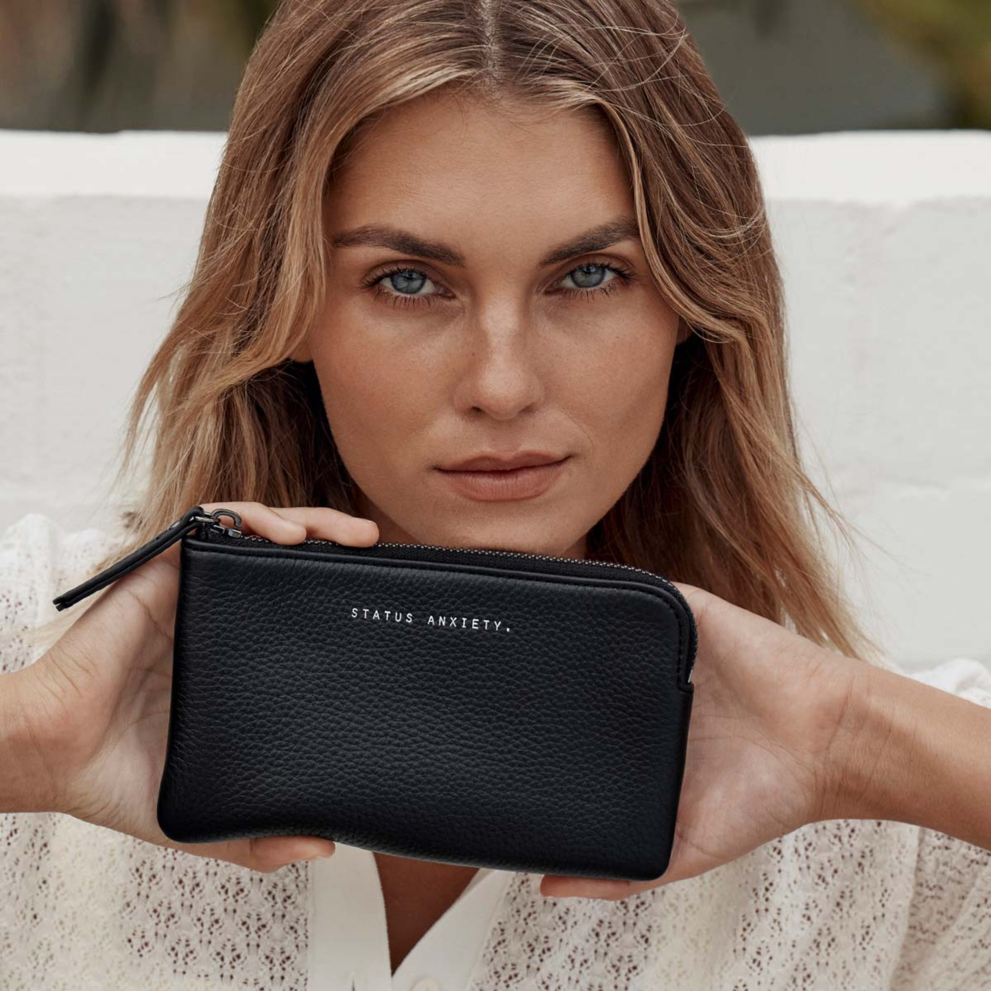 Front view of the Status Anxiety Wallet Smoke And Mirrors Black from soft shrunken pebble leather with 4 card slots, held by a woman.