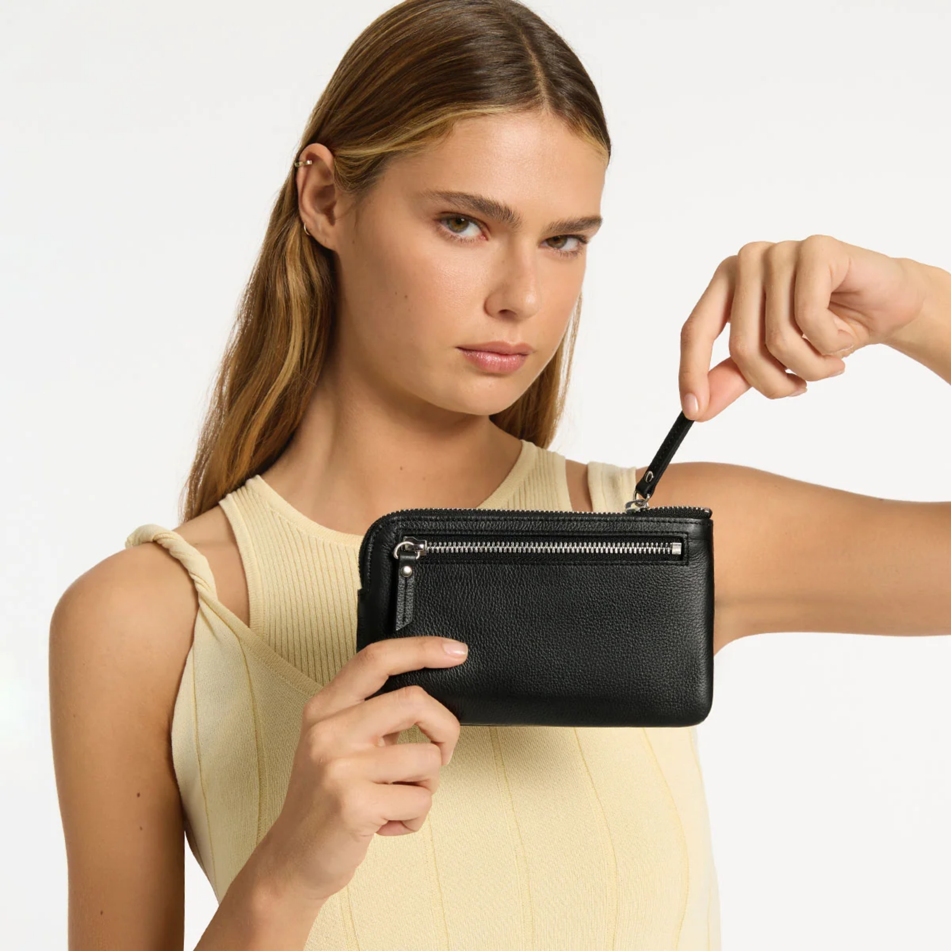 Back view of the Status Anxiety Wallet Smoke And Mirrors Black from soft shrunken pebble leather with 4 card slots, held by a woman.