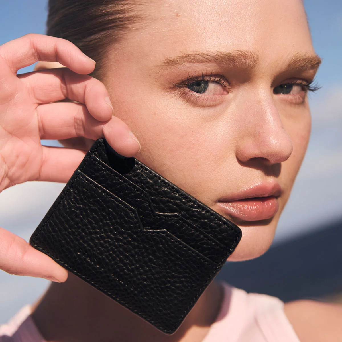 Status Anxiety Wallet Together For Now Black Soft shrunken pebble leather with 4 card slots and stash pocket, held face level of a woman.