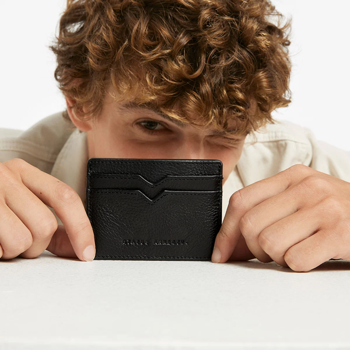 Status Anxiety Wallet Together For Now Black Soft shrunken pebble leather with 4 card slots and stash pocket, held covering the man's mouth.