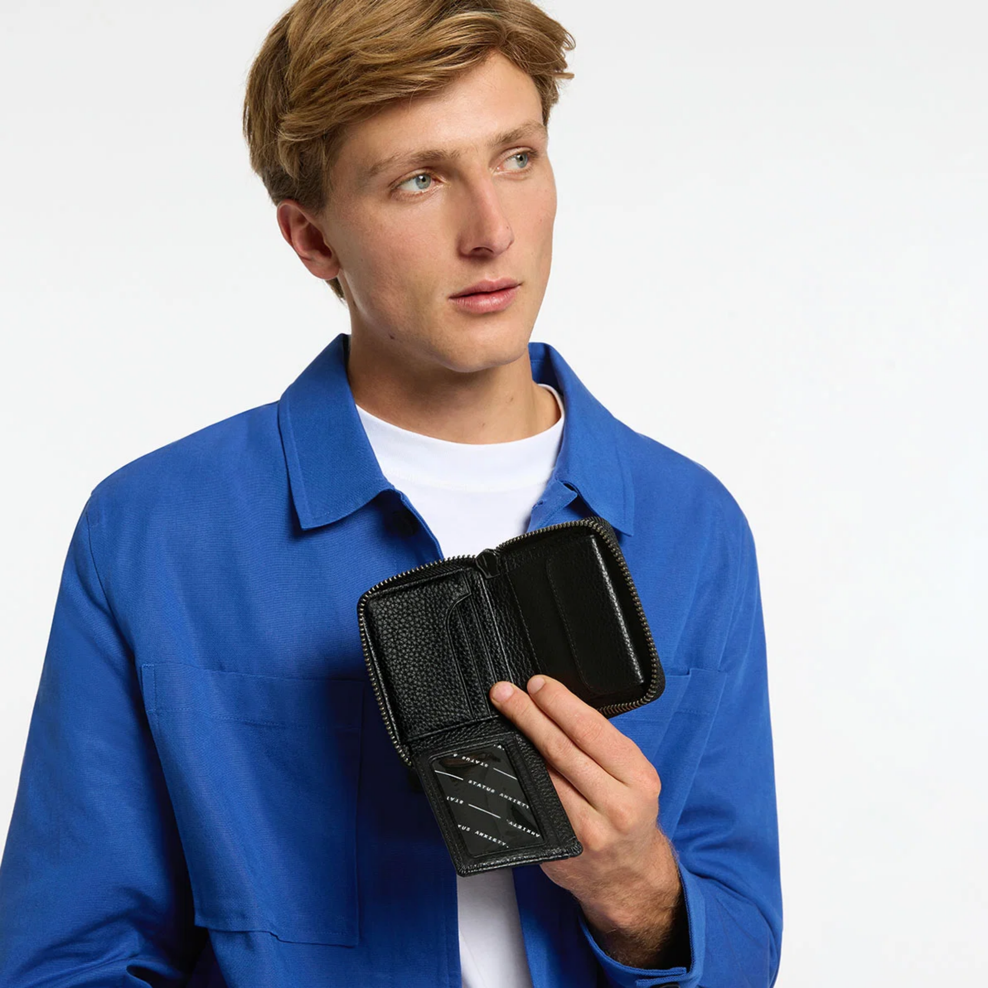 Open Status Anxiety Wallet Wayward Black from shrunken pebble leather with zipper, silver foil logo and 9 slots, held chest level.