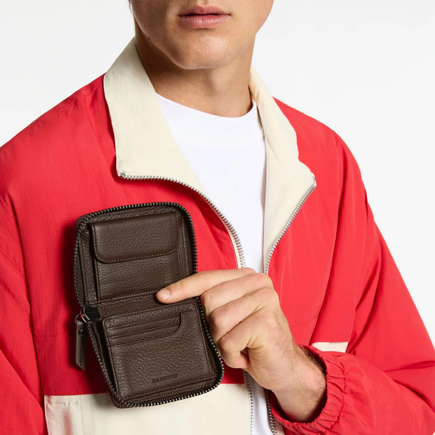Open Status Anxiety Wallet Wayward Cocoa from shrunken pebble leather with zipper, silver foil logo and 9 slots, held chest level.