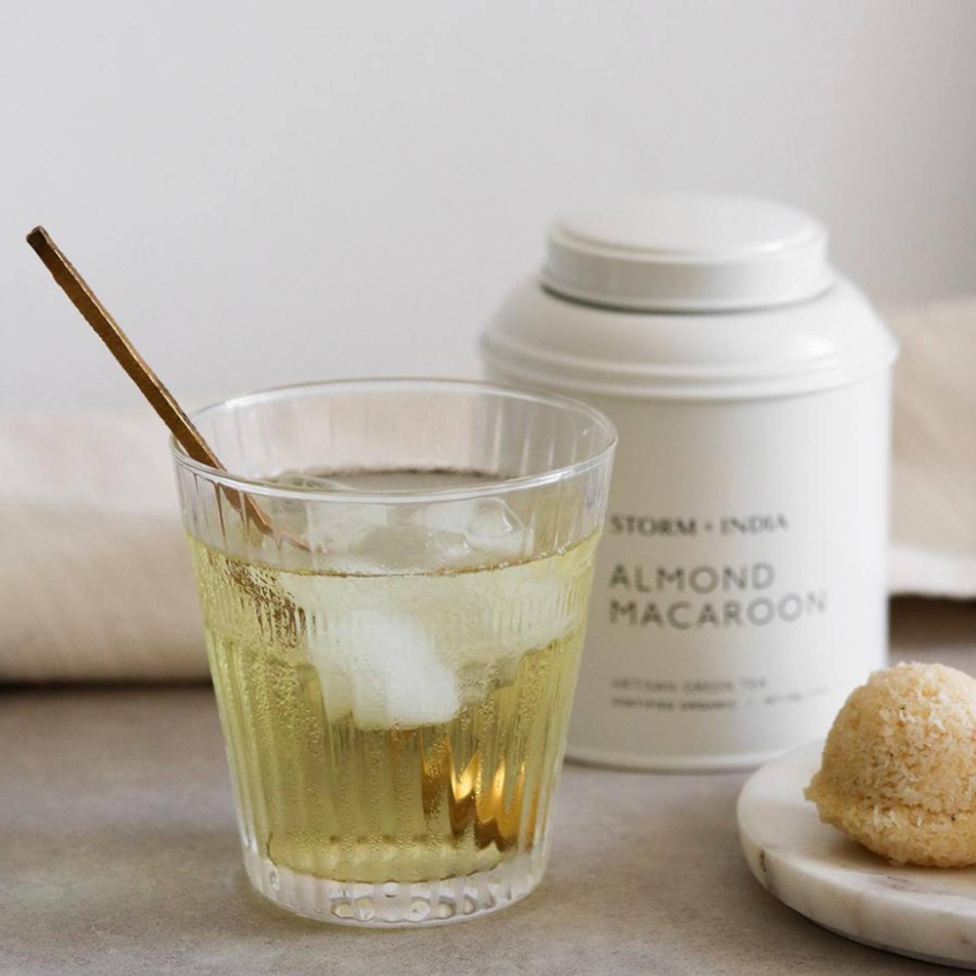 Storm and India Loose Leaf Tea in Tin 150g Almond Macaroon on table with glass of iced tea