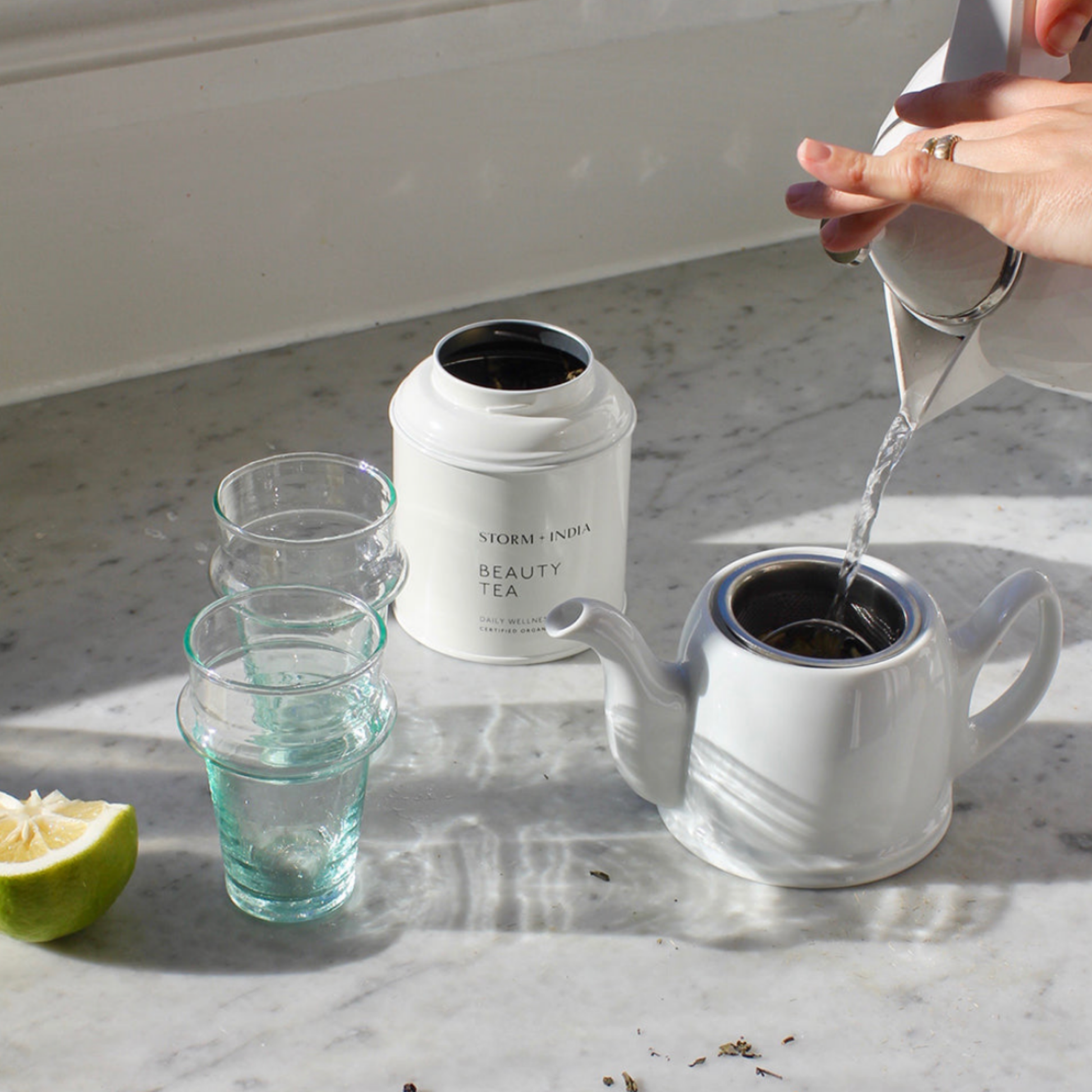 Storm and India Loose Leaf Tea in Tin 100g Beauty Tea being brewed on marble kitchen bench with teapot and glasses 