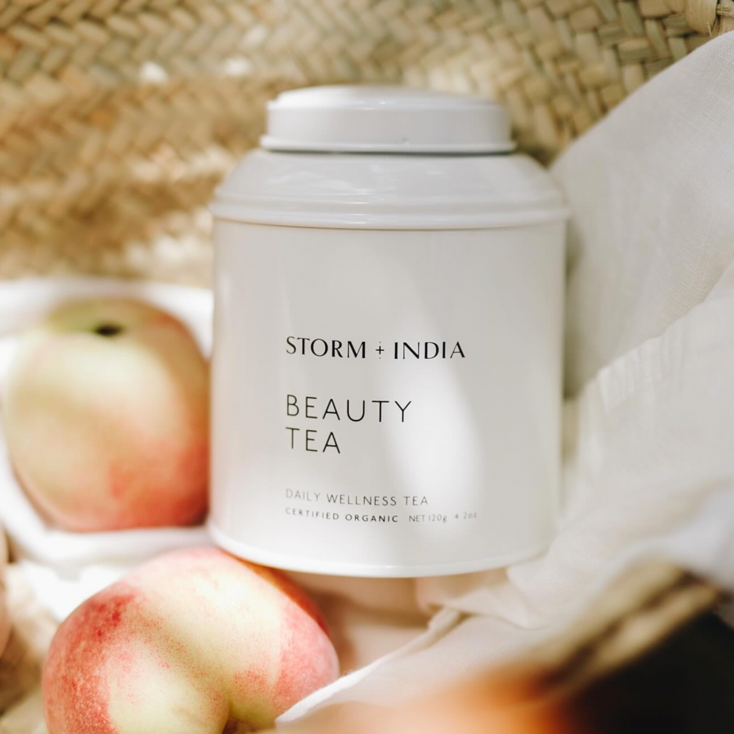 Storm and India Loose Leaf Tea in Tin 100g Beauty Tea in woven basket with table cloth and peaches 